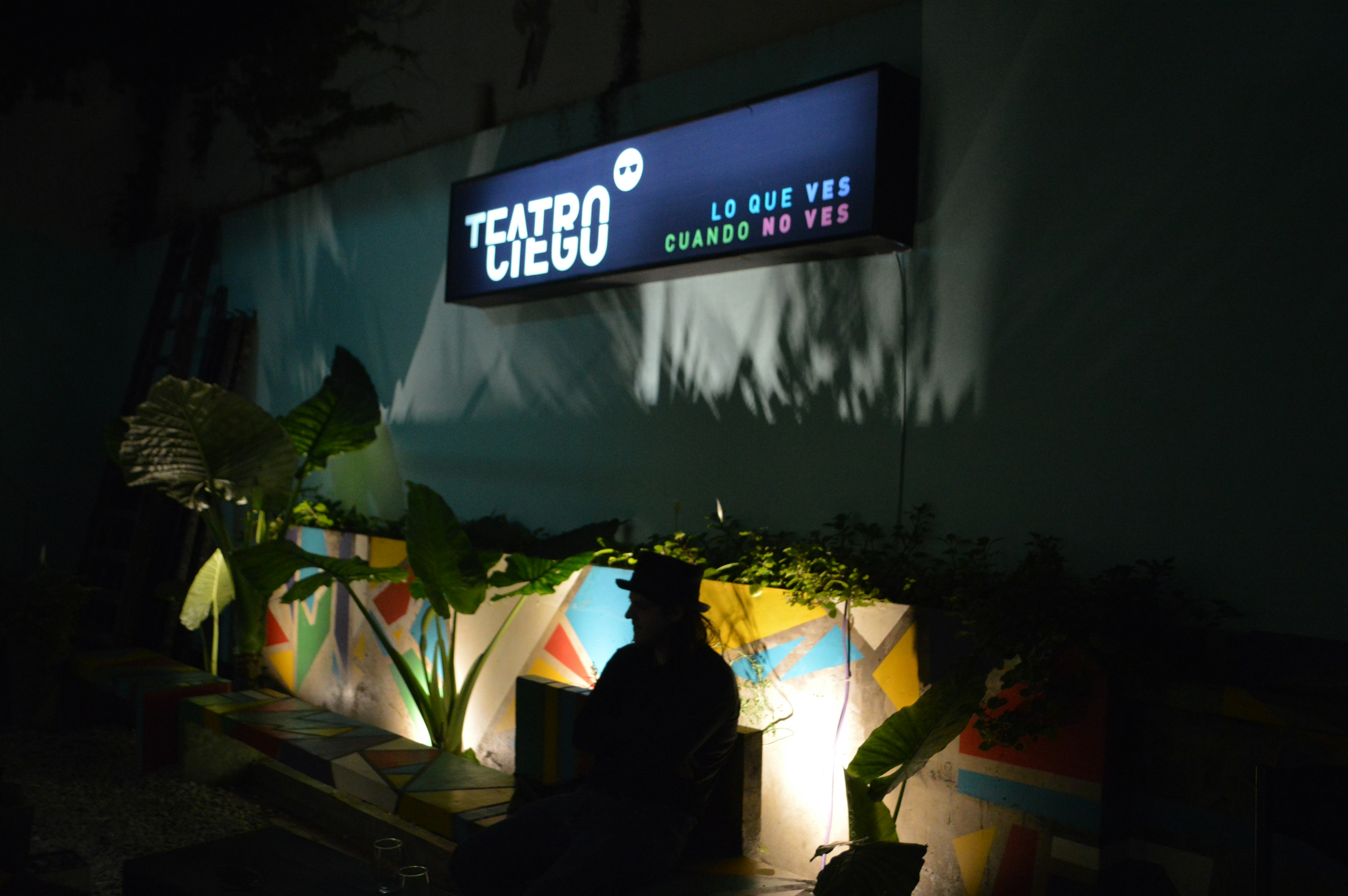 A man wearing a top hat is back lit in front of Teatro Ciego (blind theater) in Buenos Aires