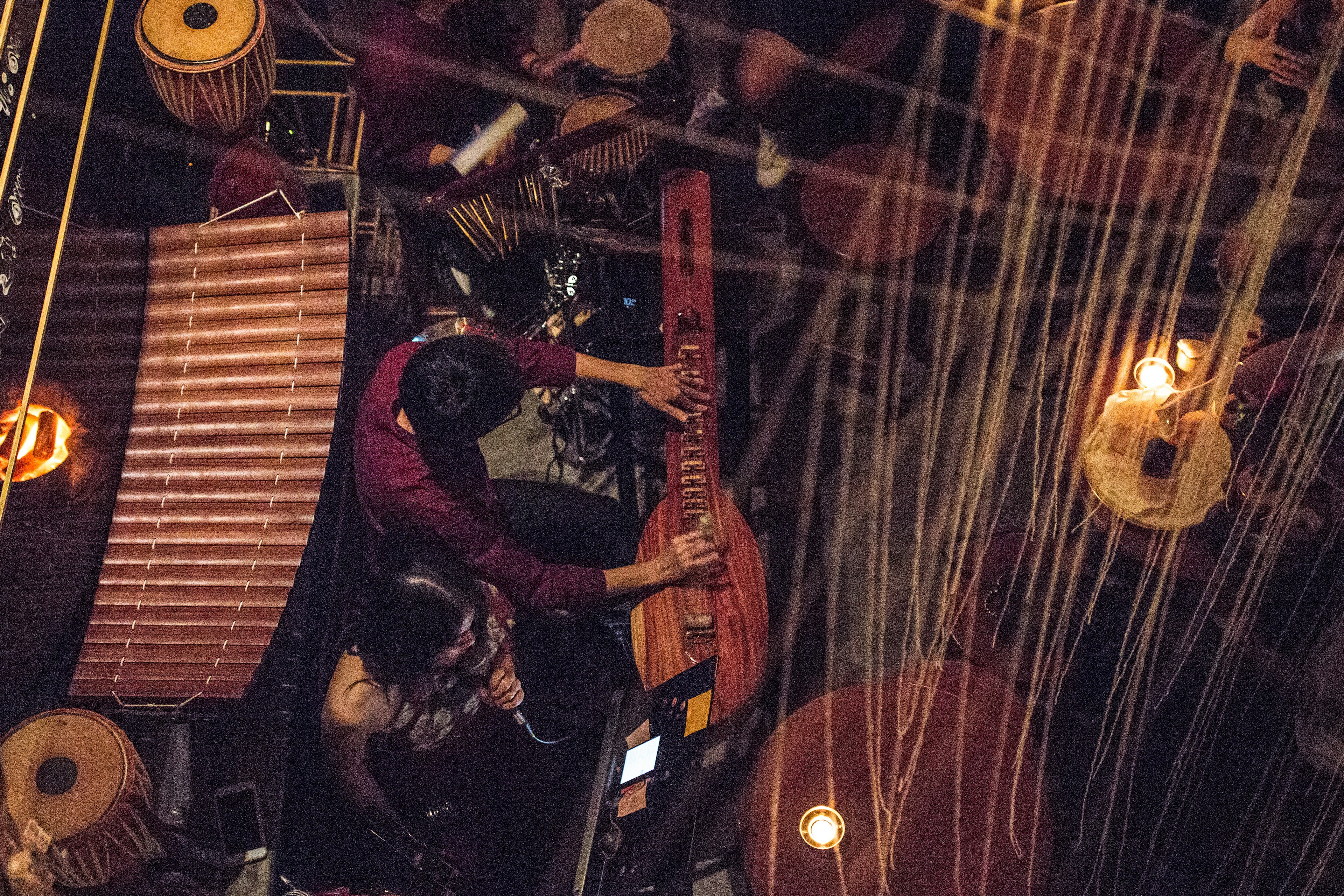 A man playing a guitar-like instrument sits next to a woman who is singing, in Tep Bar