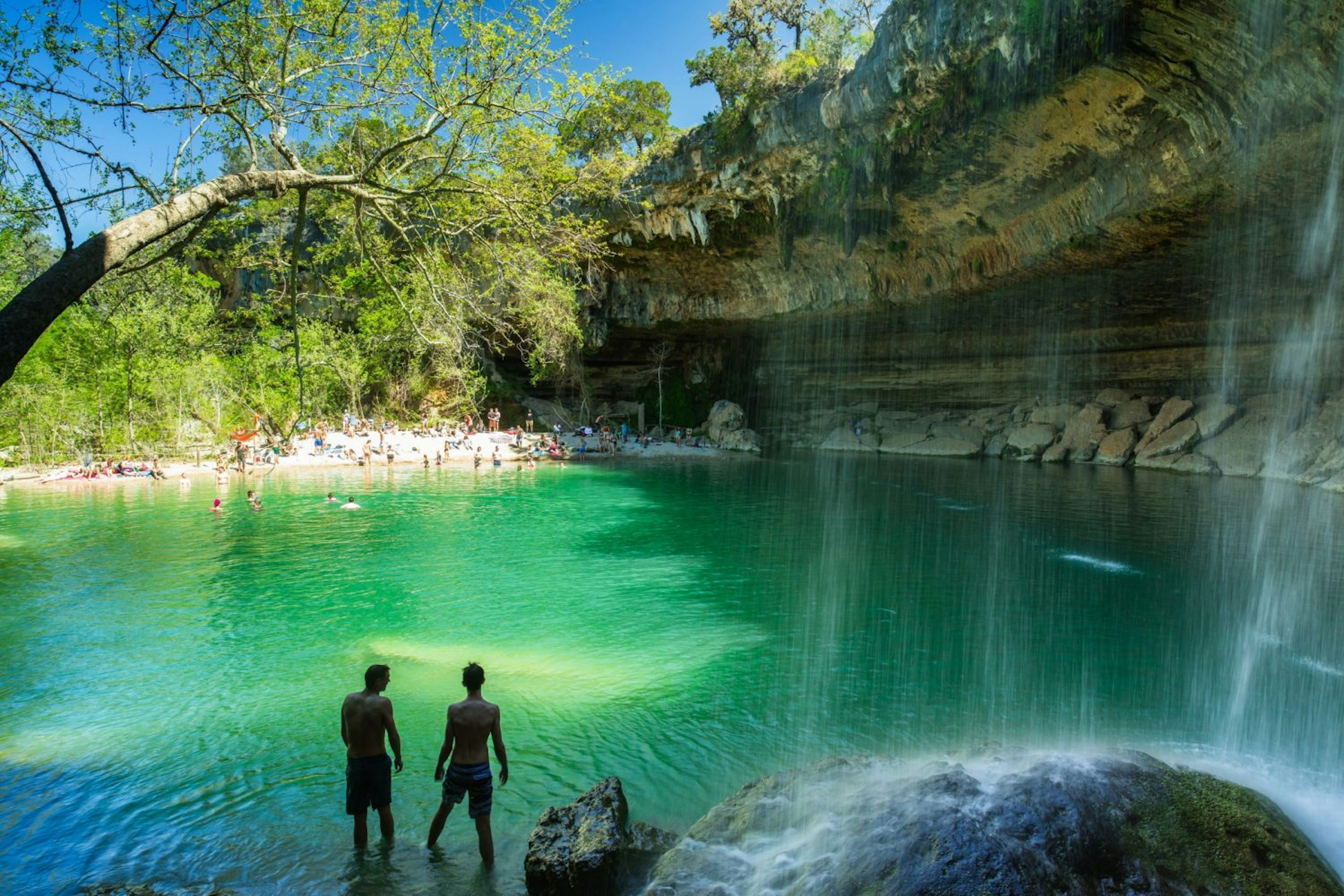 People swimming at the natural Hamilton Pool in rural Travis County, Texas.