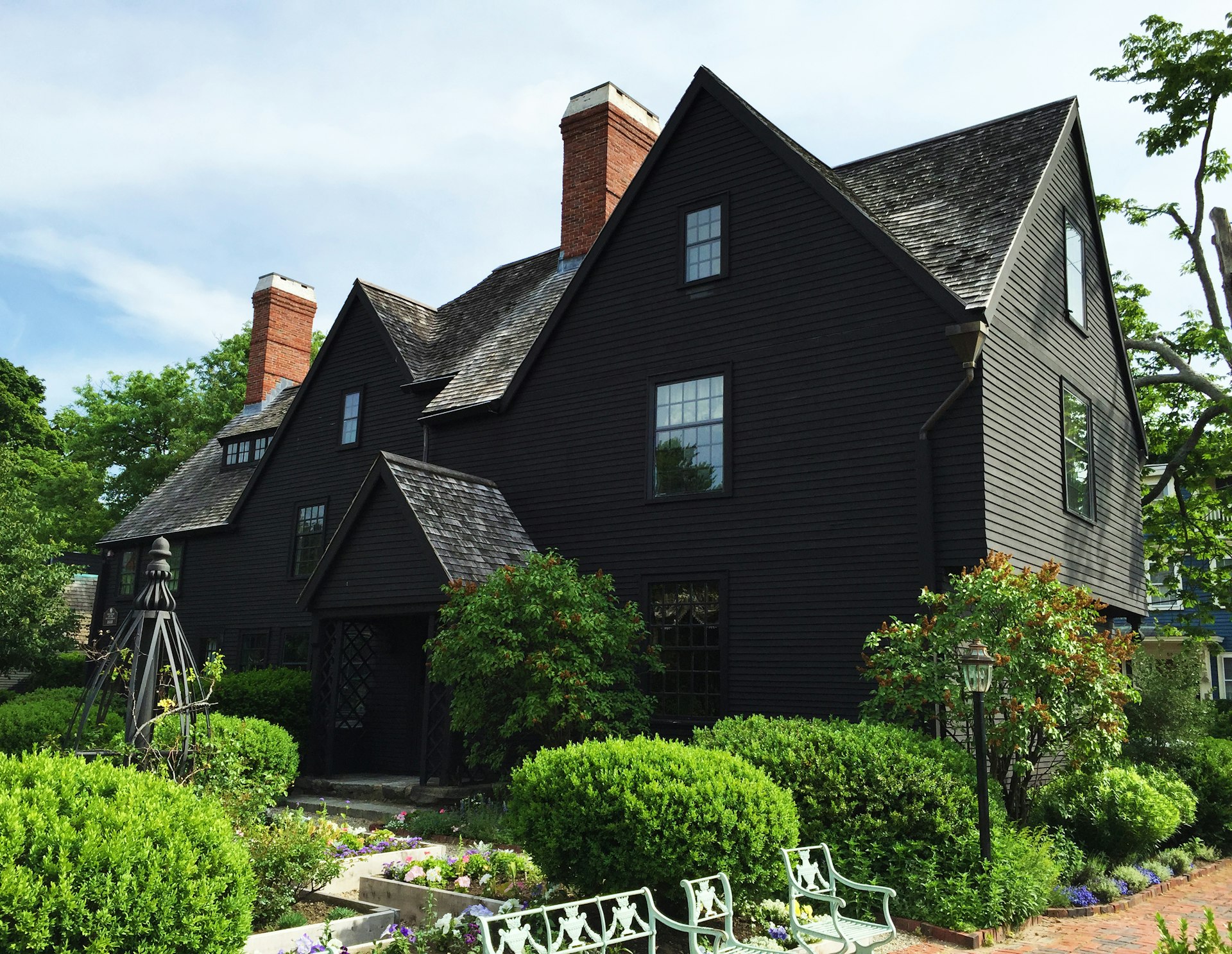 A black wooden house with several distinct peaks or gables and a neat garden 