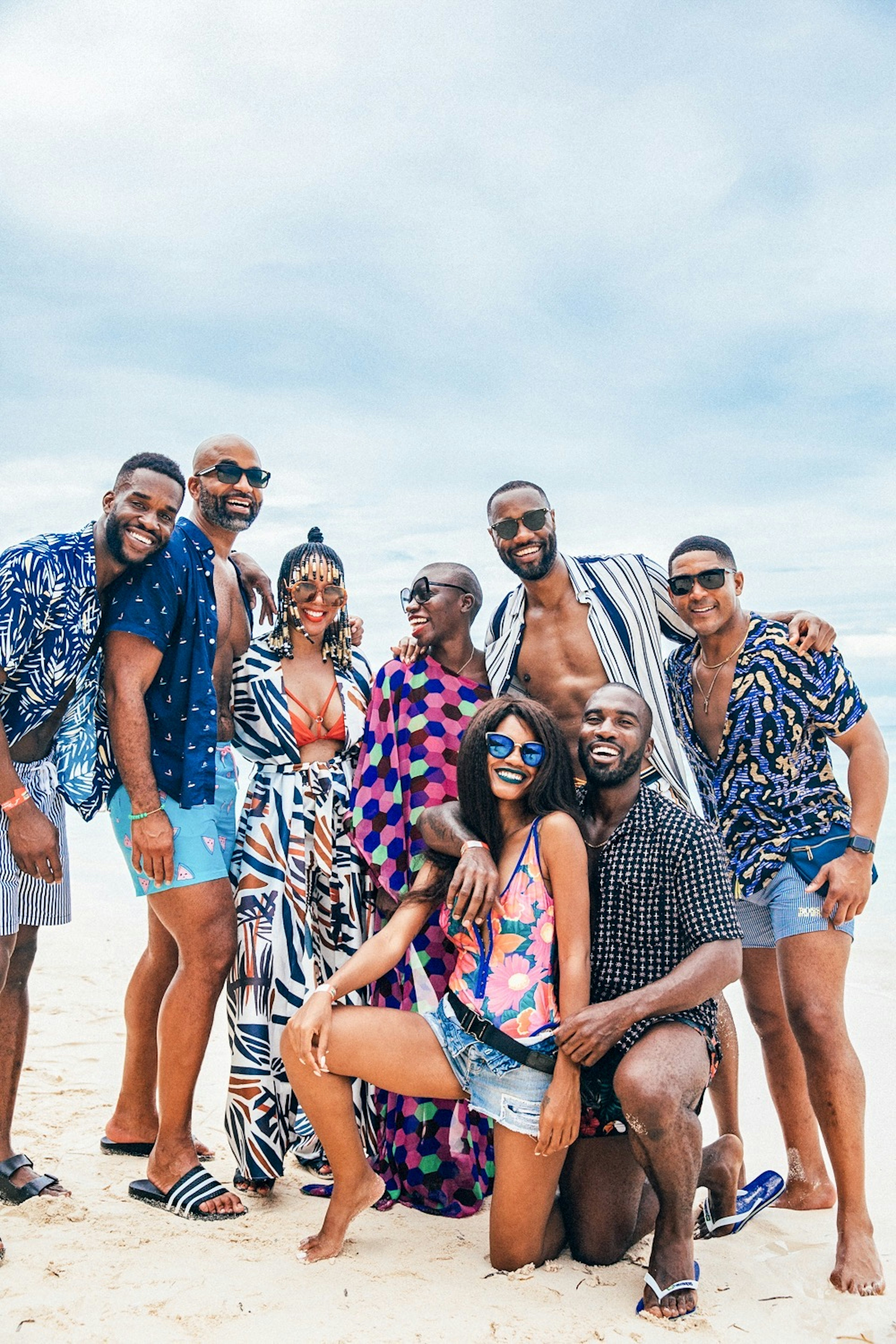 A group of people smiling and posing on the beach in the Seychelles to celebrate Jessica Nabongo travelling to every country in the world