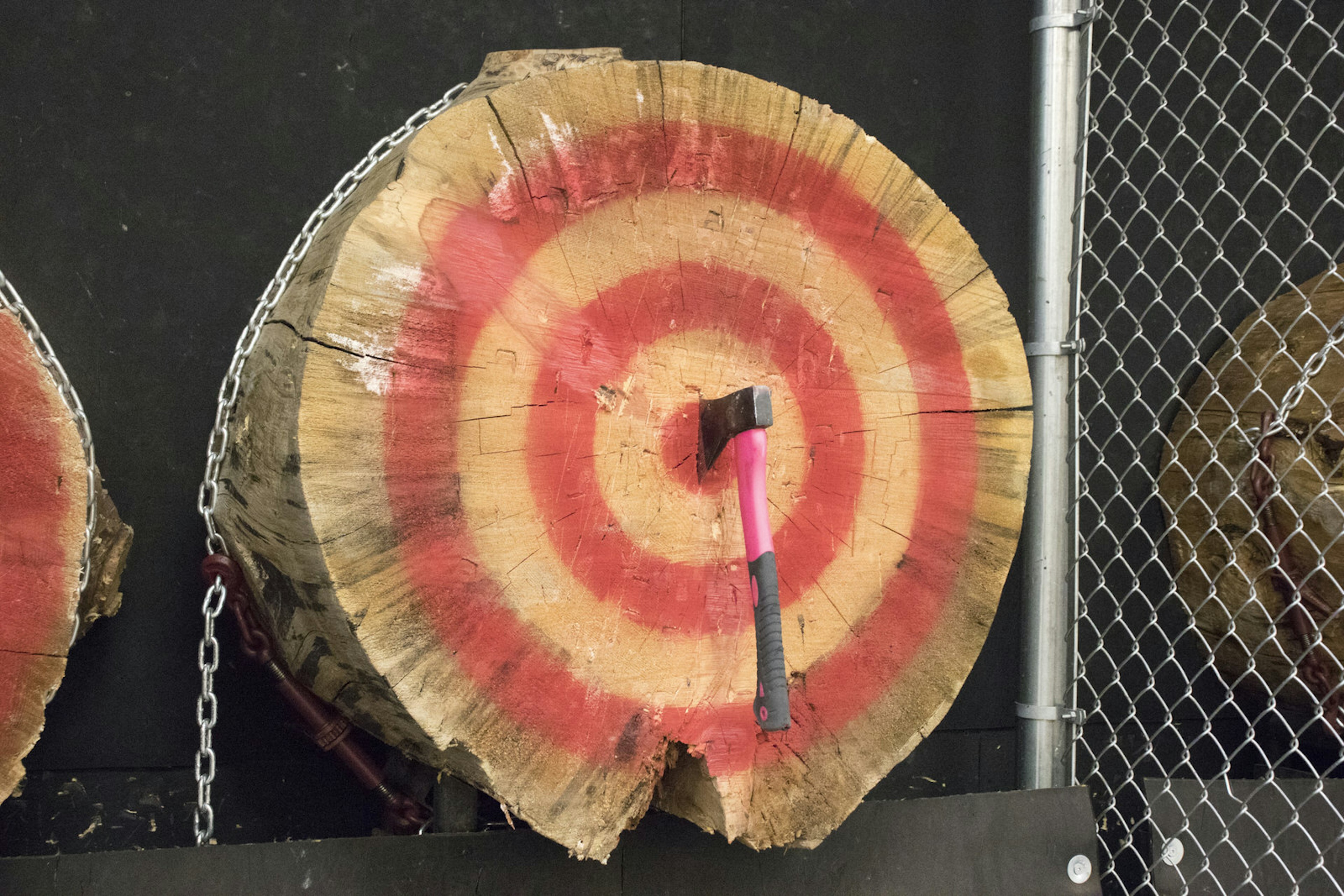 A recently-thrown axe is lodged directly in the middle of a huge log face, with a red target painted on it © Greg Thilmont / Lonely Planet