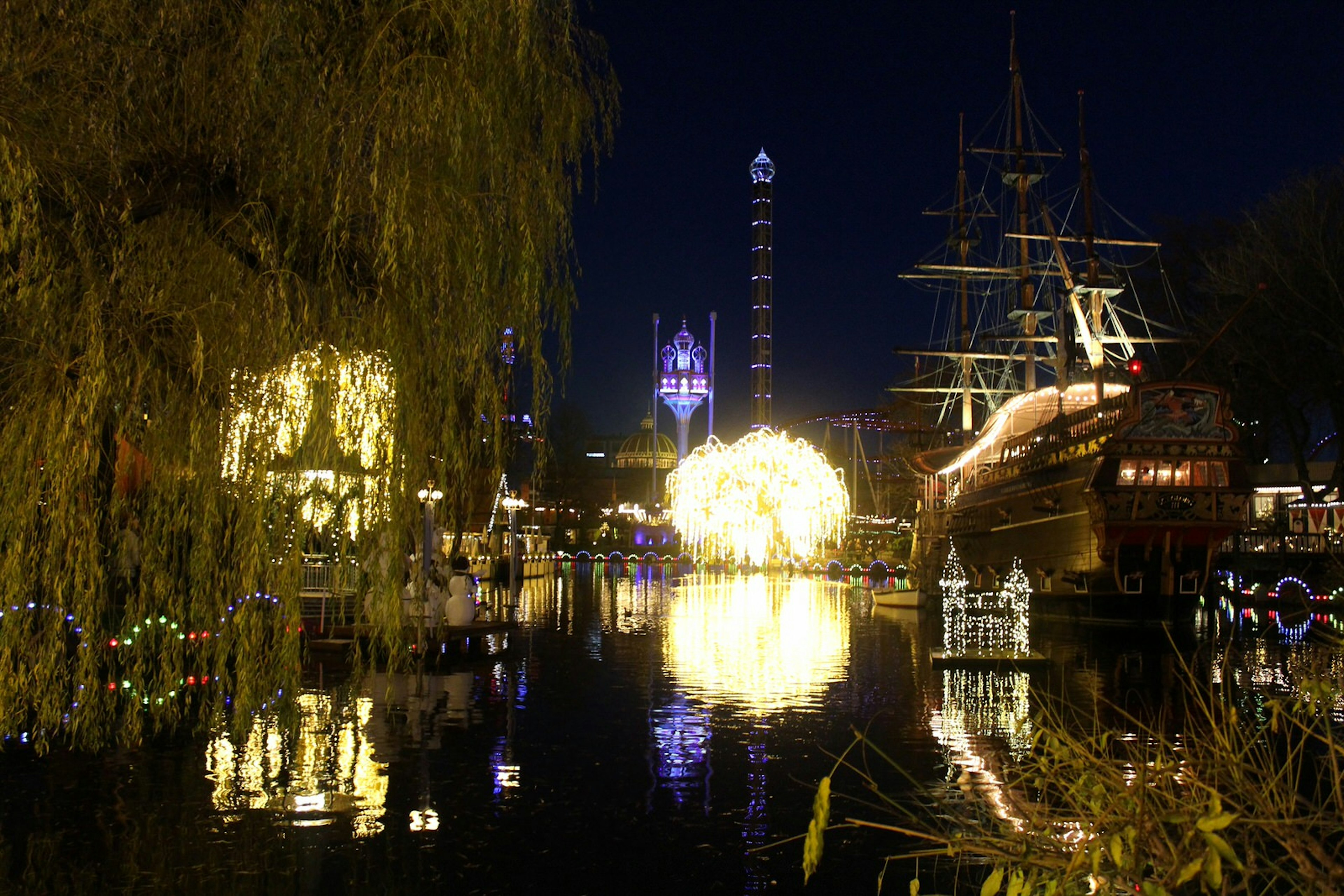 Tivoli at night, with colourfully-illuminated buildings and a water and light show © Caroline Hadamitzky / iBestTravel