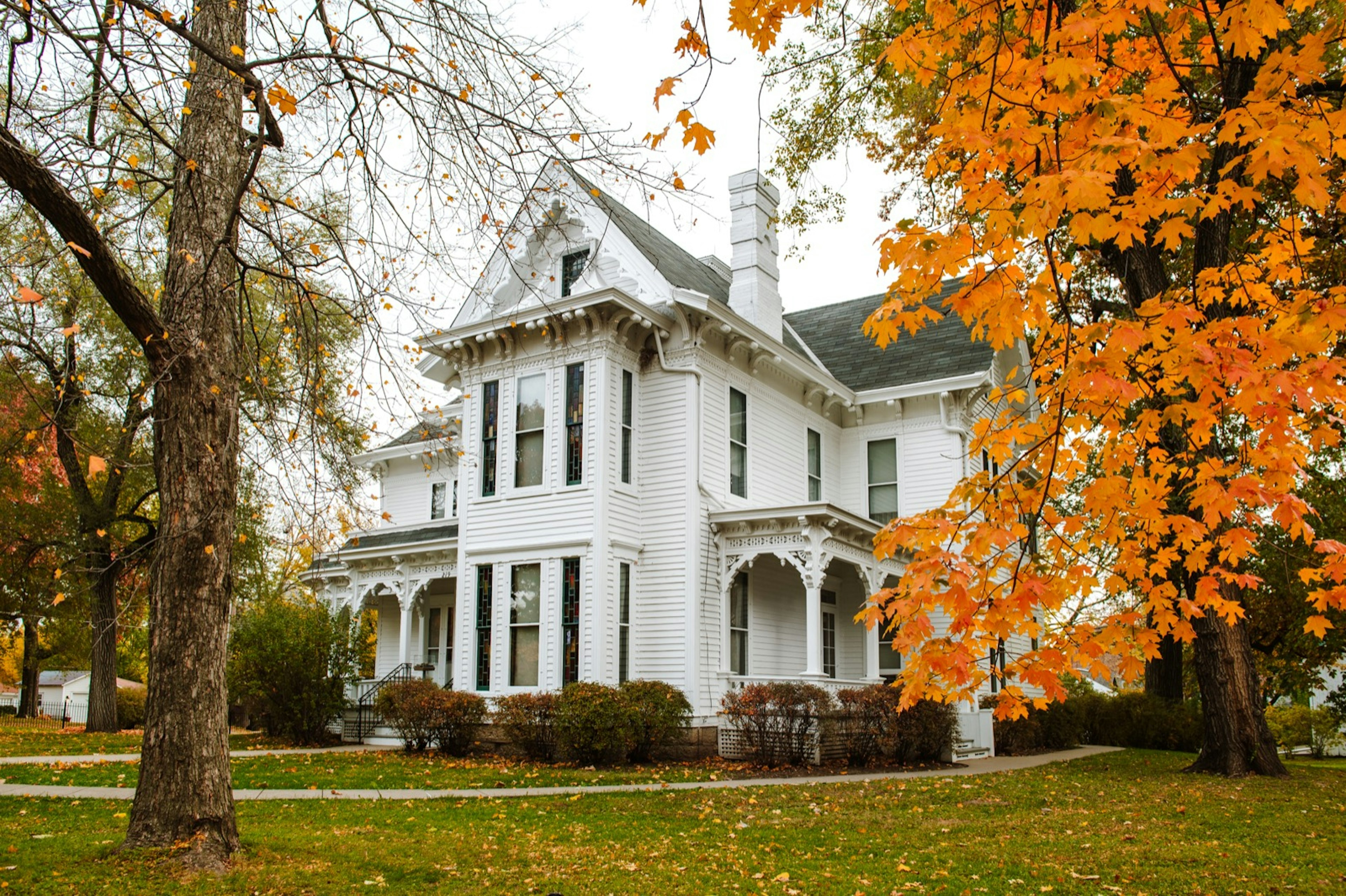 The white facade of the Truman House surrounded by orange leaves; historic homes