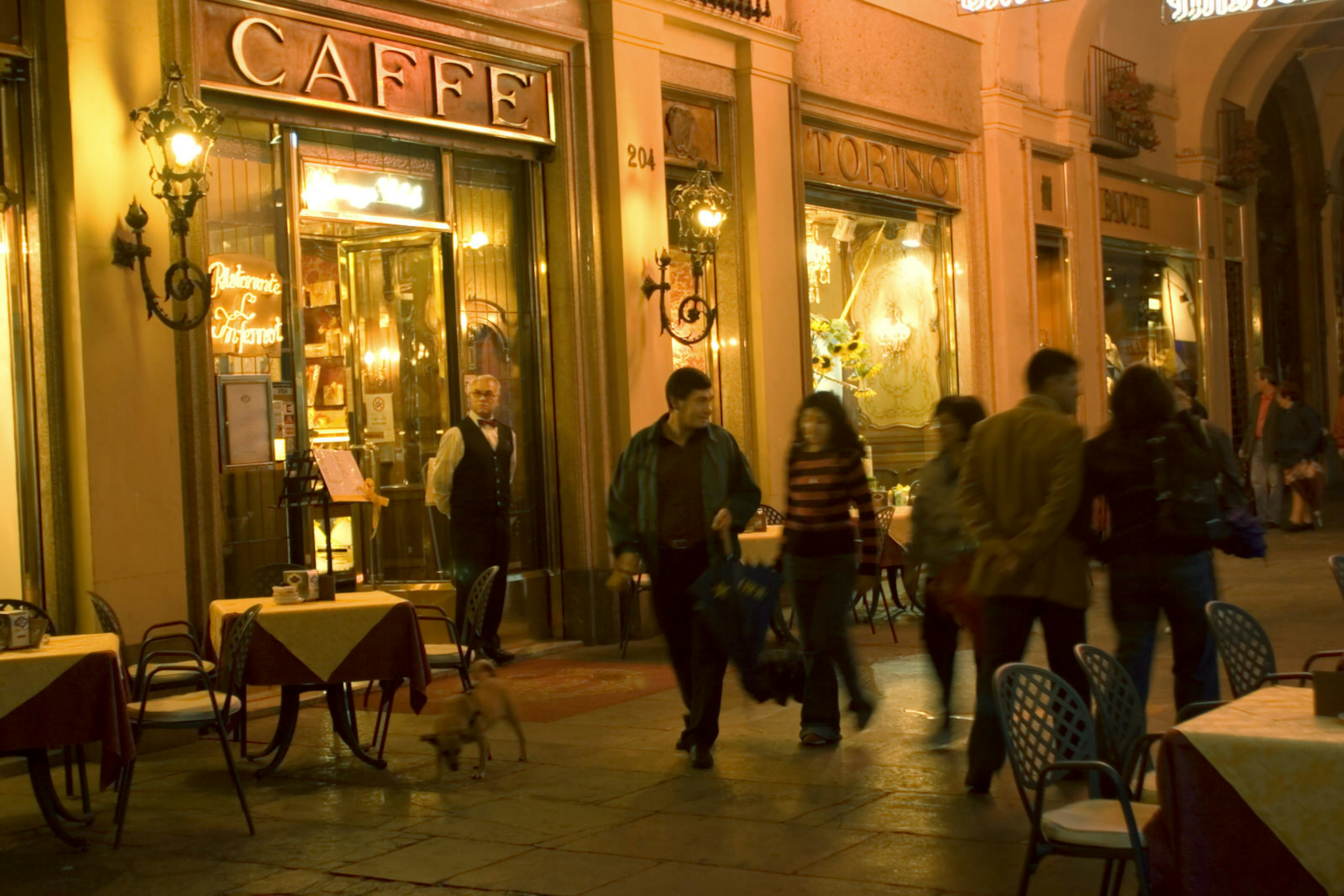 People walk past the Belle Epoque facade of Caffè Torino at night © Bob Sacha / Getty Images