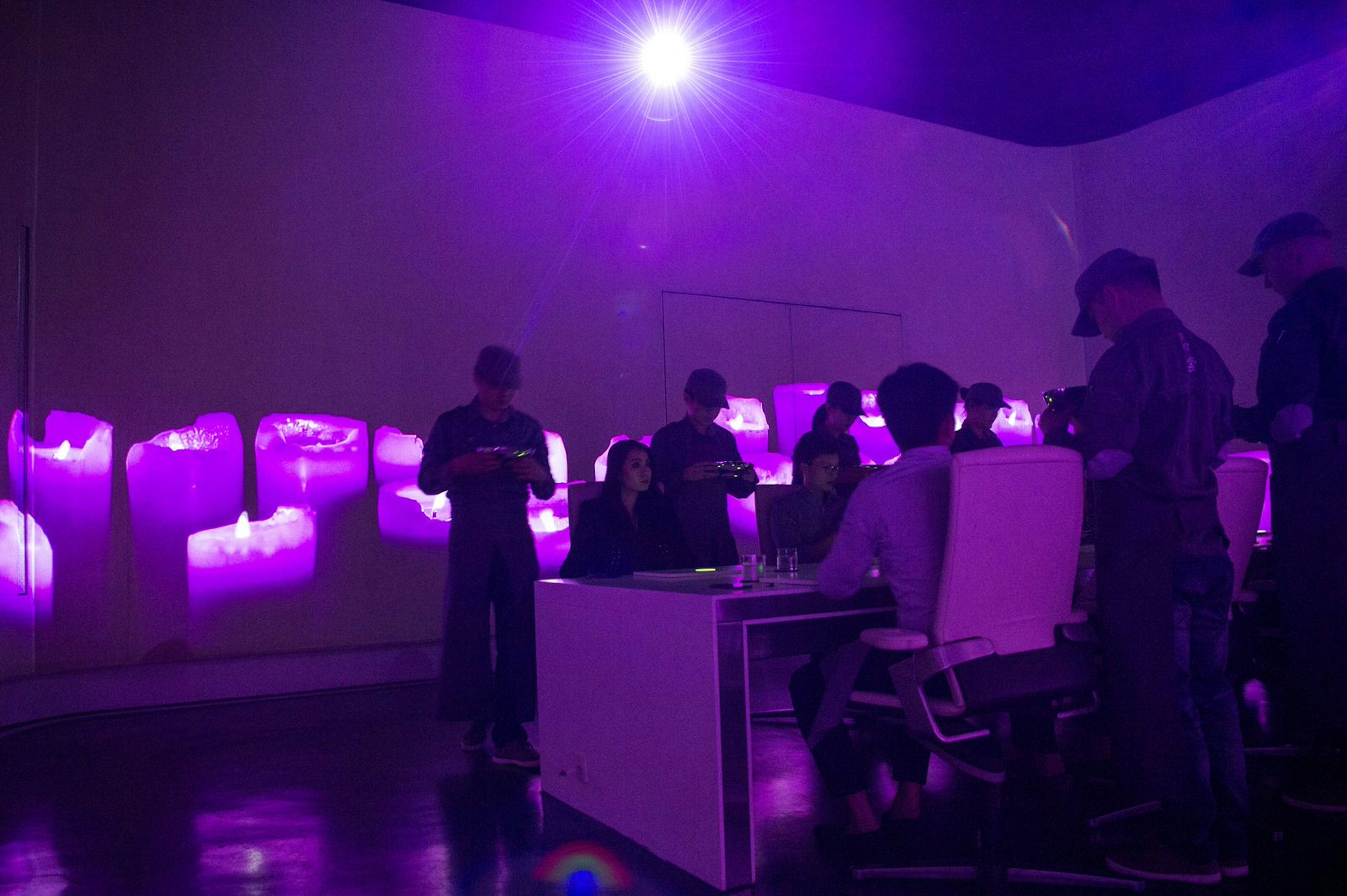 Staff members of Ultraviolet restaurant serve their guests inside the dining room in Shanghai which is illuminated by a violet light