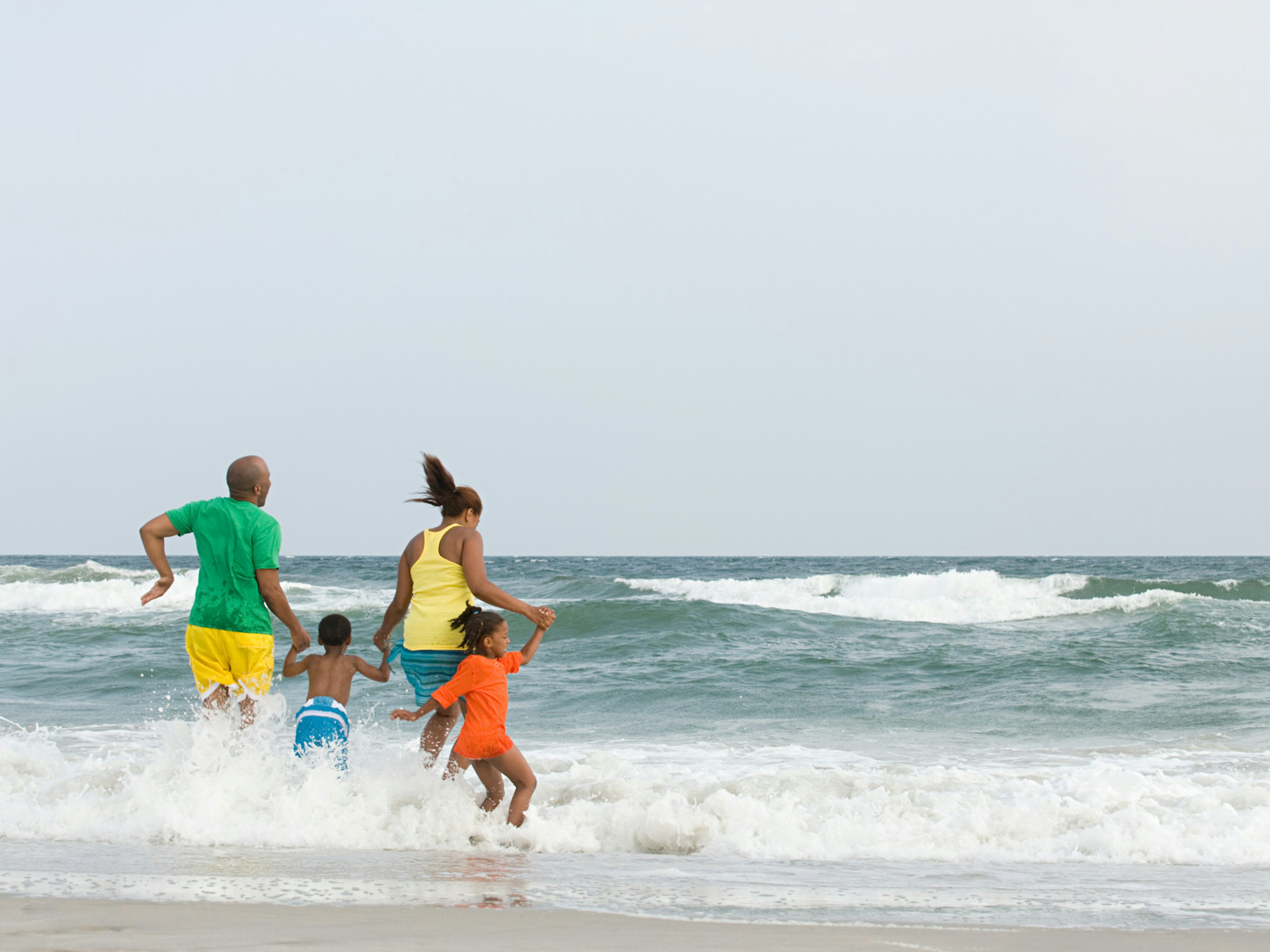 A family of four running into the ocean