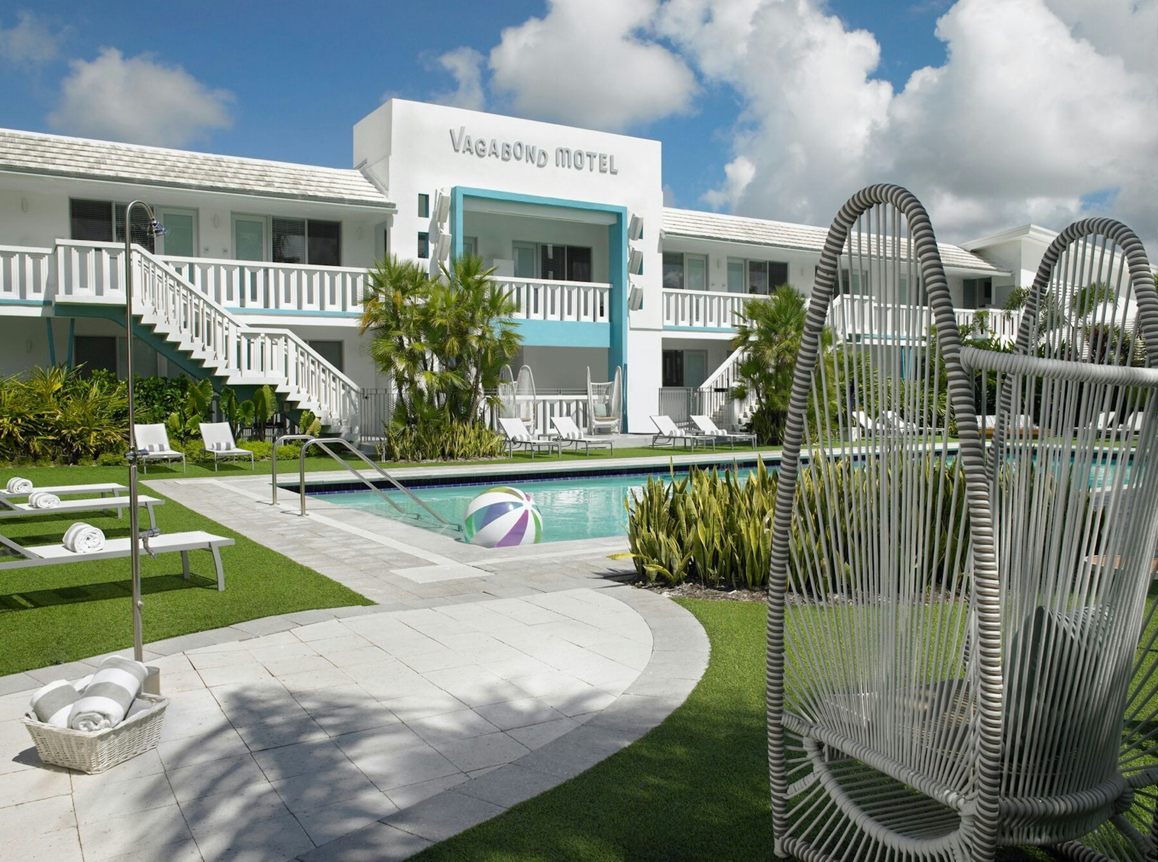 Exterior of Vagabond Motel and pool, with lounge chairs and green grass, coolest motels