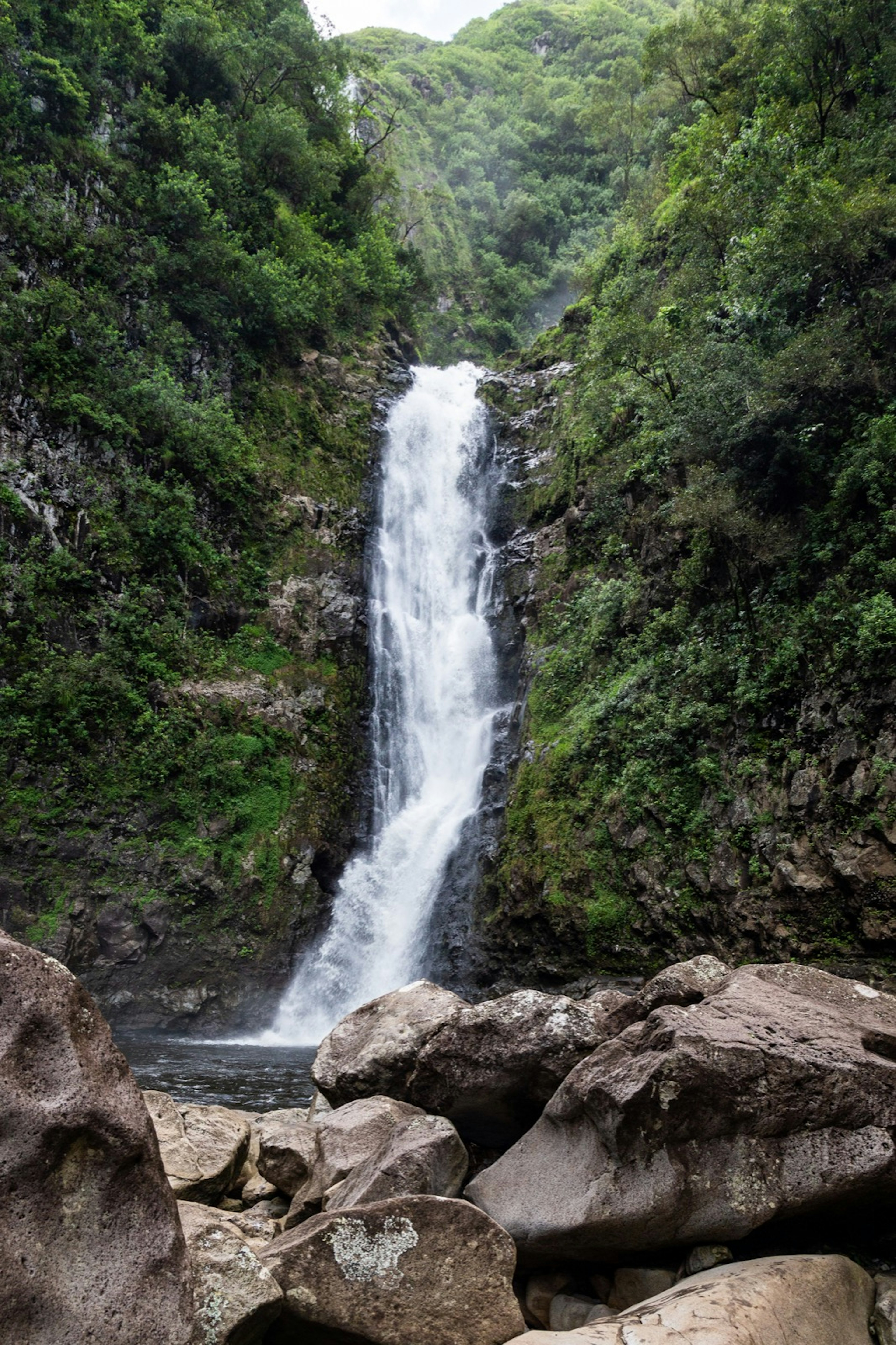 Large rocks guard the entrance to a pool with a double-tiered waterfall behind