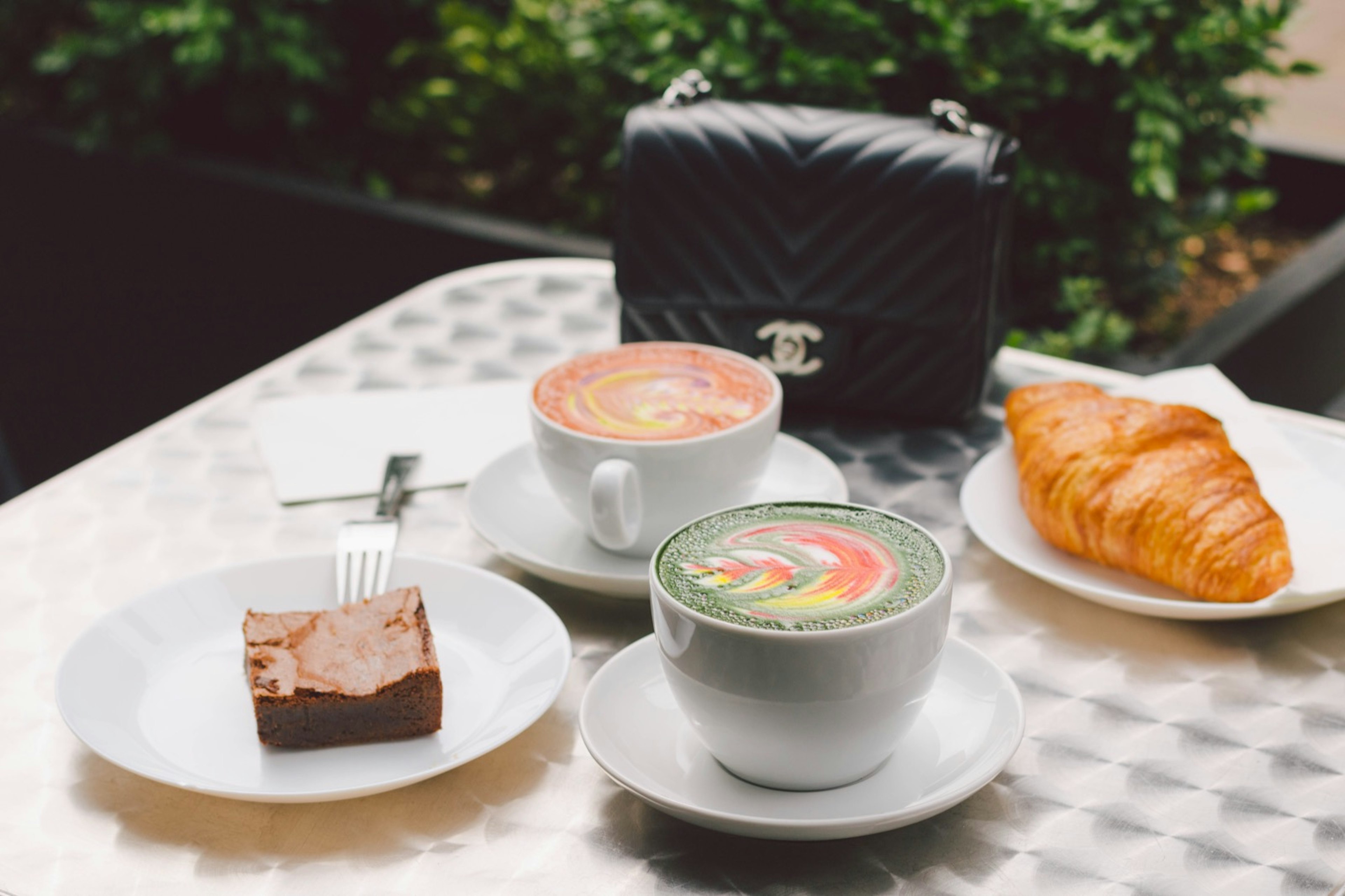 Coffee in a variety of rainbow colors and swirled with cream patterns sits on a table © Jessica Lam / ϰϲʿ¼