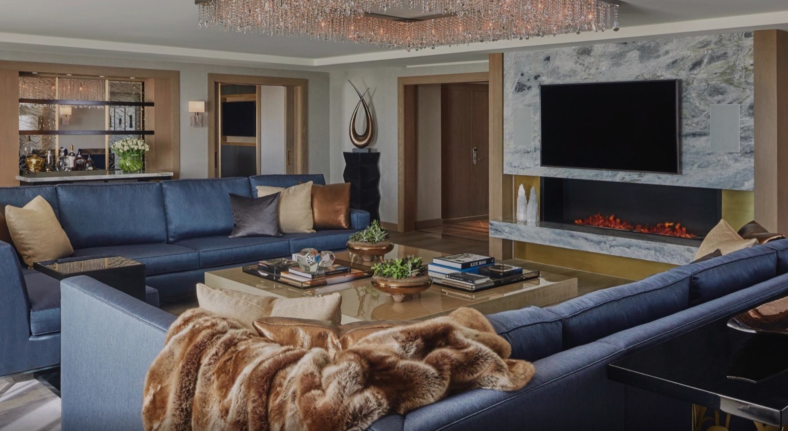 A living area featuring two facing couches and a large TV over a marble fireplace