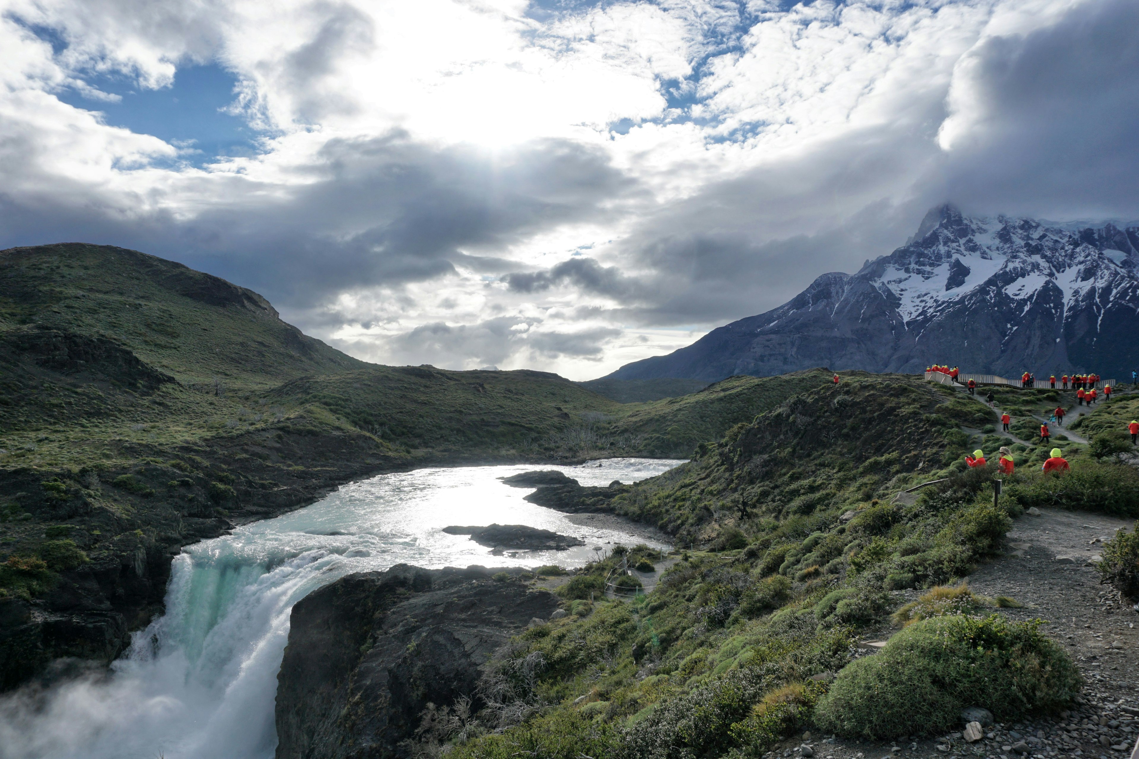 Tourists in red cruise-line issued parkas overlook a magnificent waterfall in Toress Del Paine National Park in Patagonia