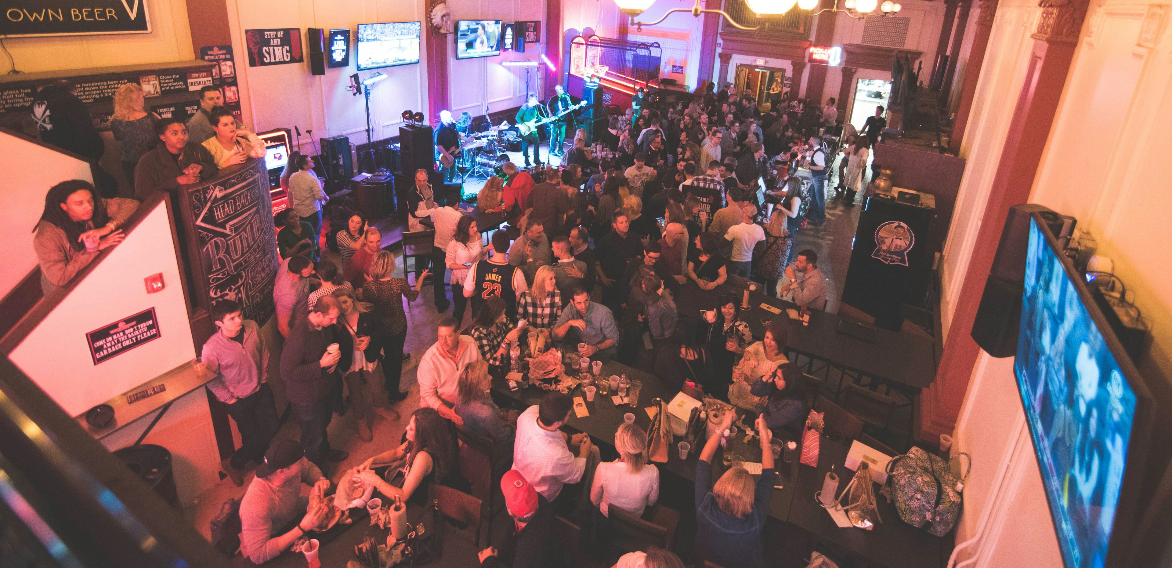 View looking down on the bar area at Wild Eagle Saloon; it's packed with patrons drinking and snacking.