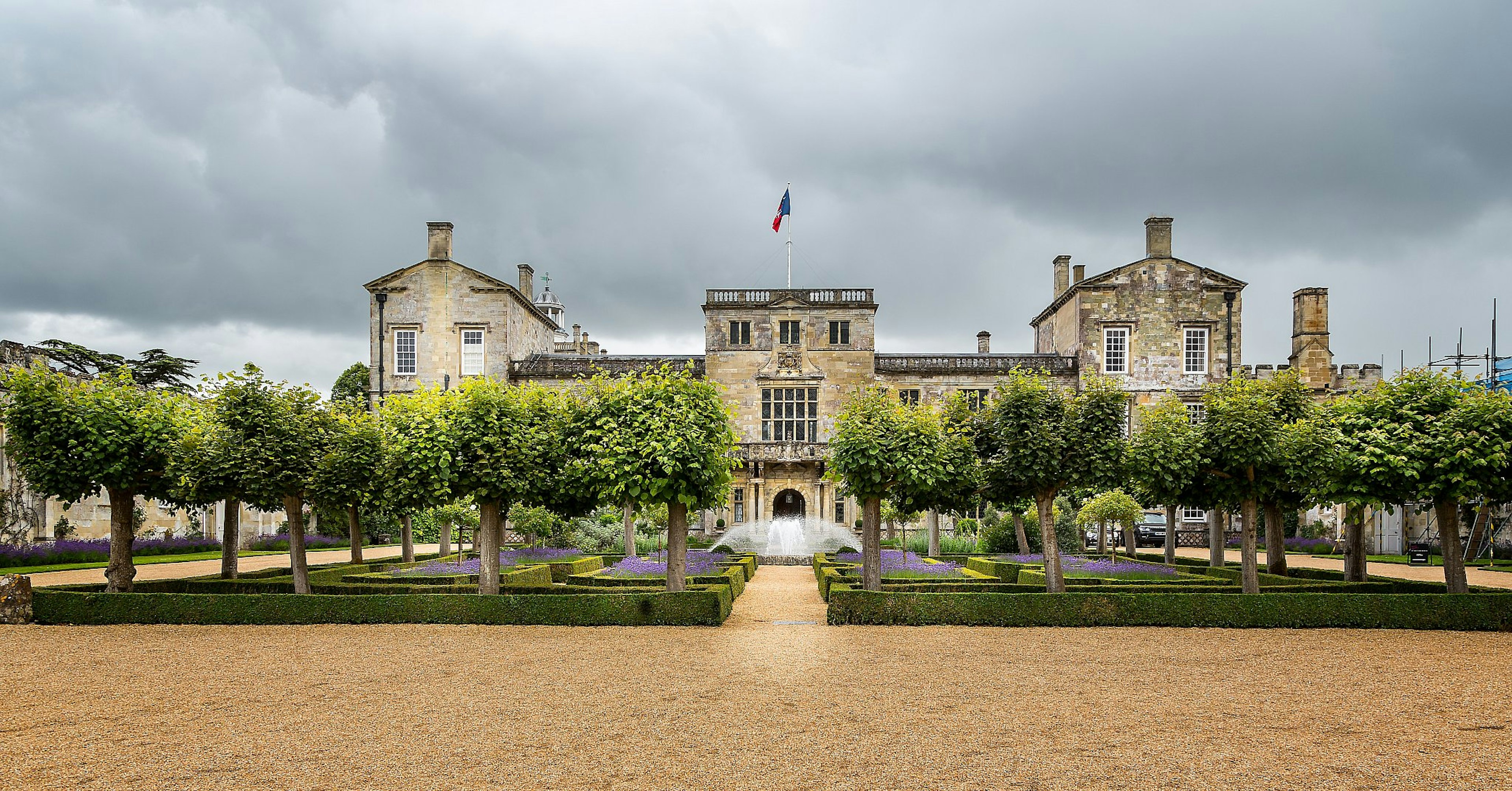 Wilton House, a stone neoclassical mansion, with a garden full of frees in front of it.