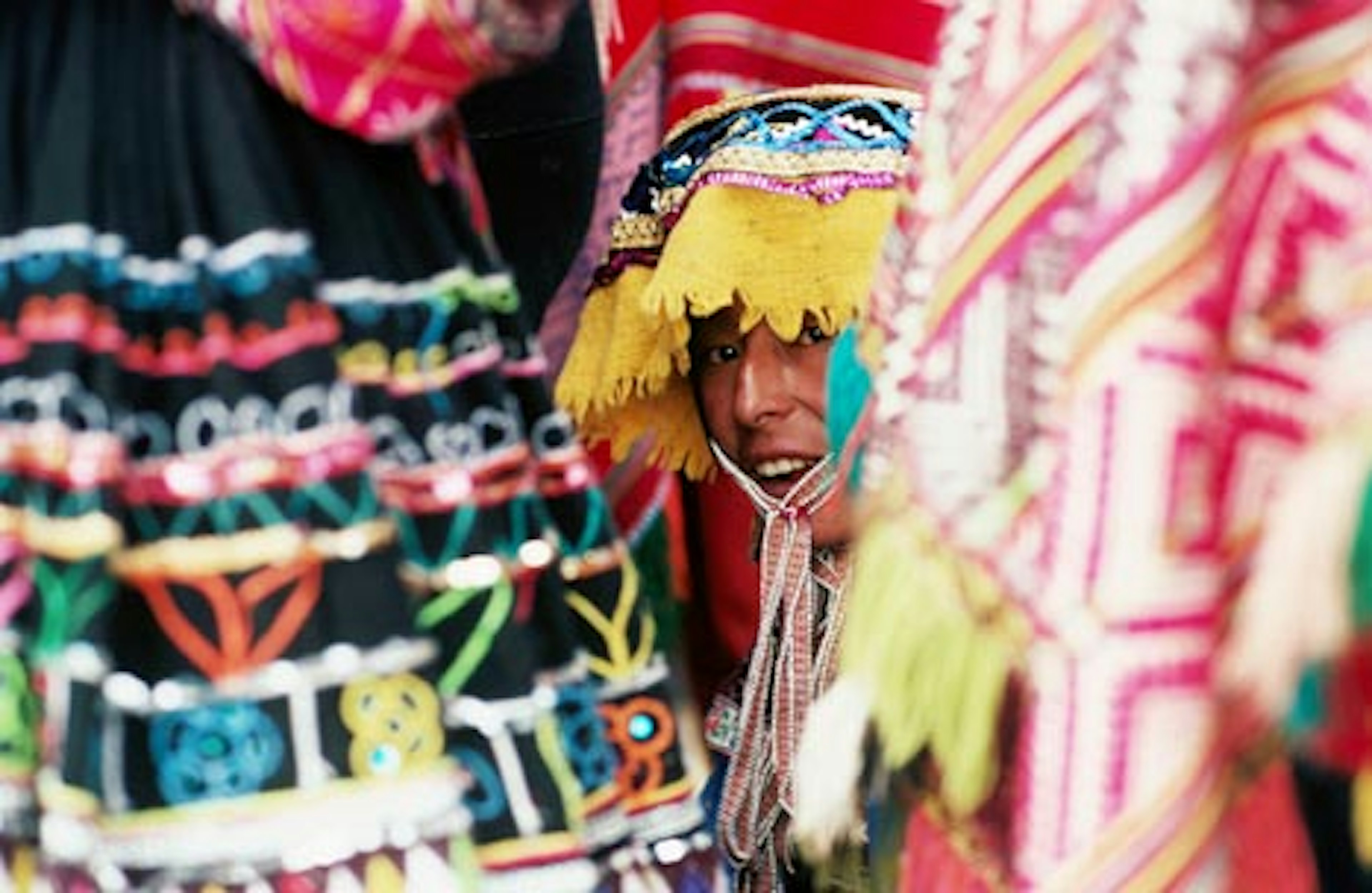 Woman in traditional hat looking through textiles and fabric of stall, Peru. Image by Richard I'Anson.