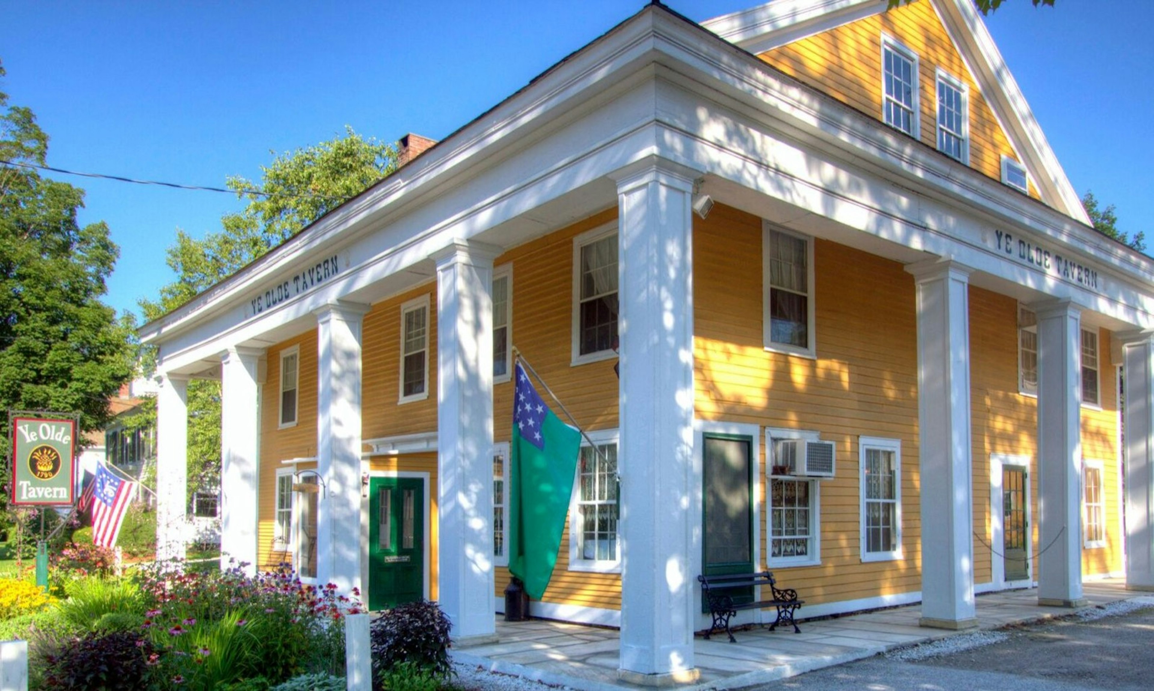 A yellow house-like building with white eaves and columns against a blue sky