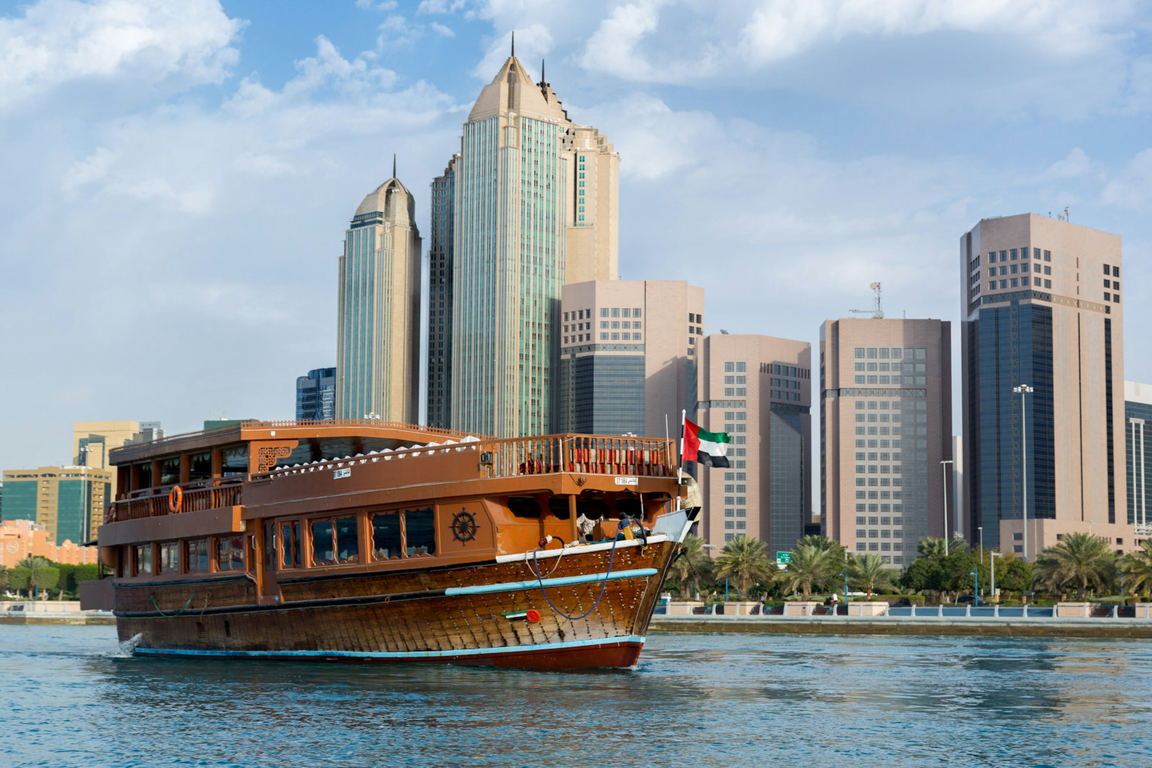 A traditional wooden boat sails past Abu Dhabi's Corniche. Image by Ali Suliman / Shutterstock