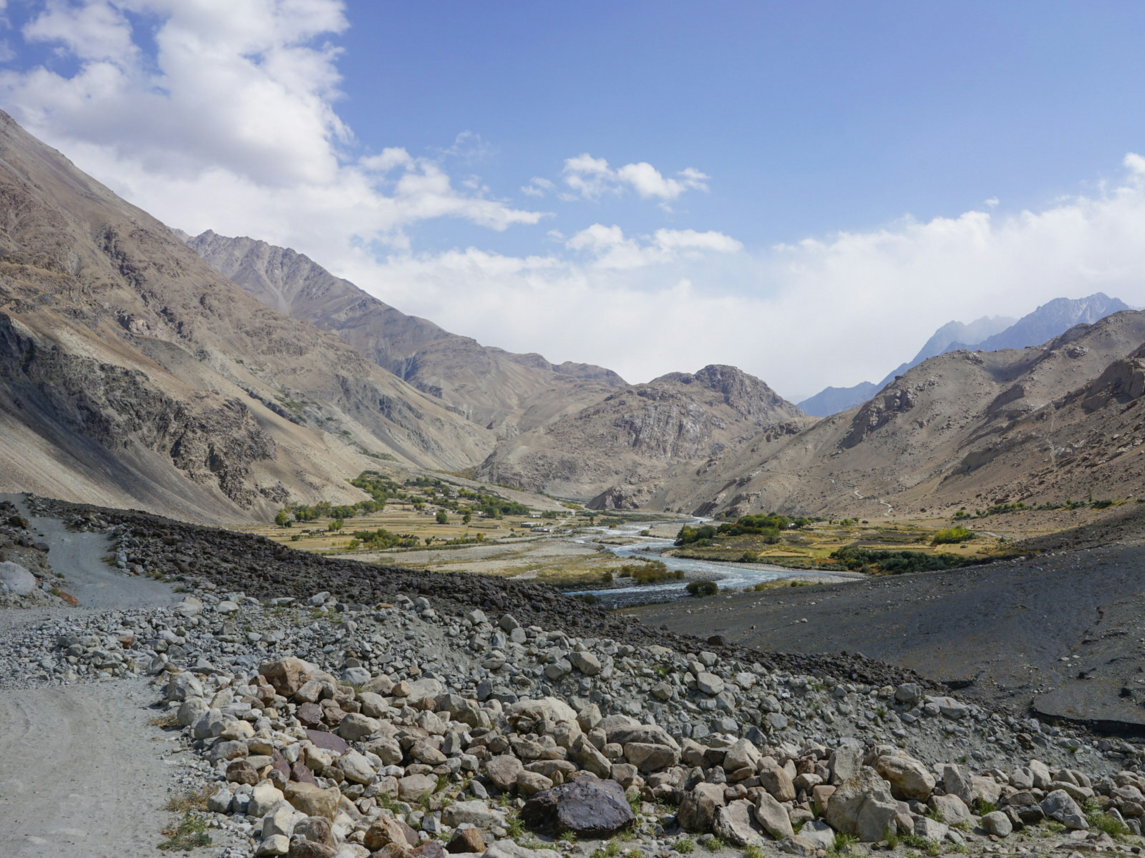 A rock-strewn landscape gives way to a river running through a dry mountain valley