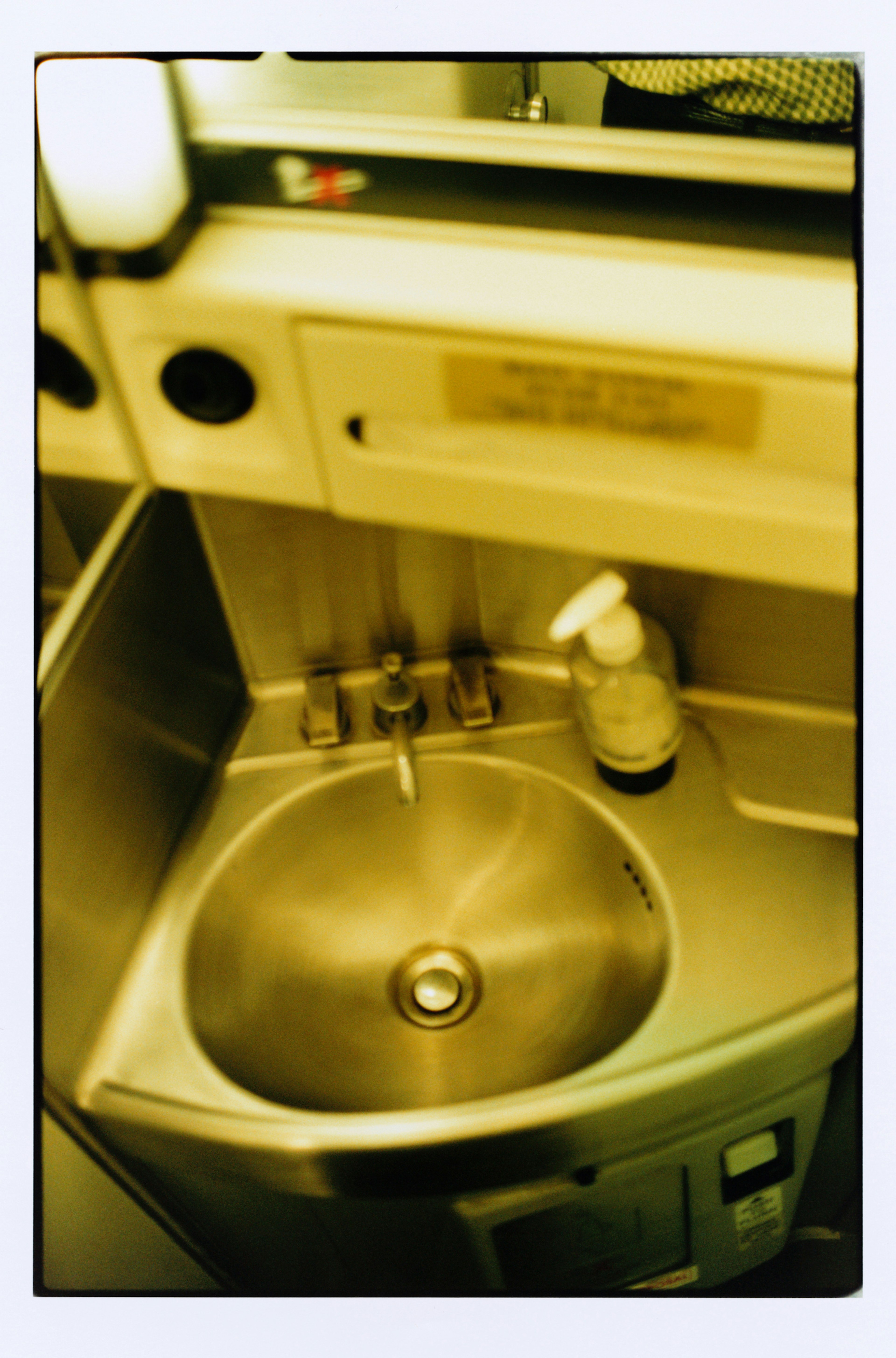 the sink and soap dispenser in an airplane toilet.