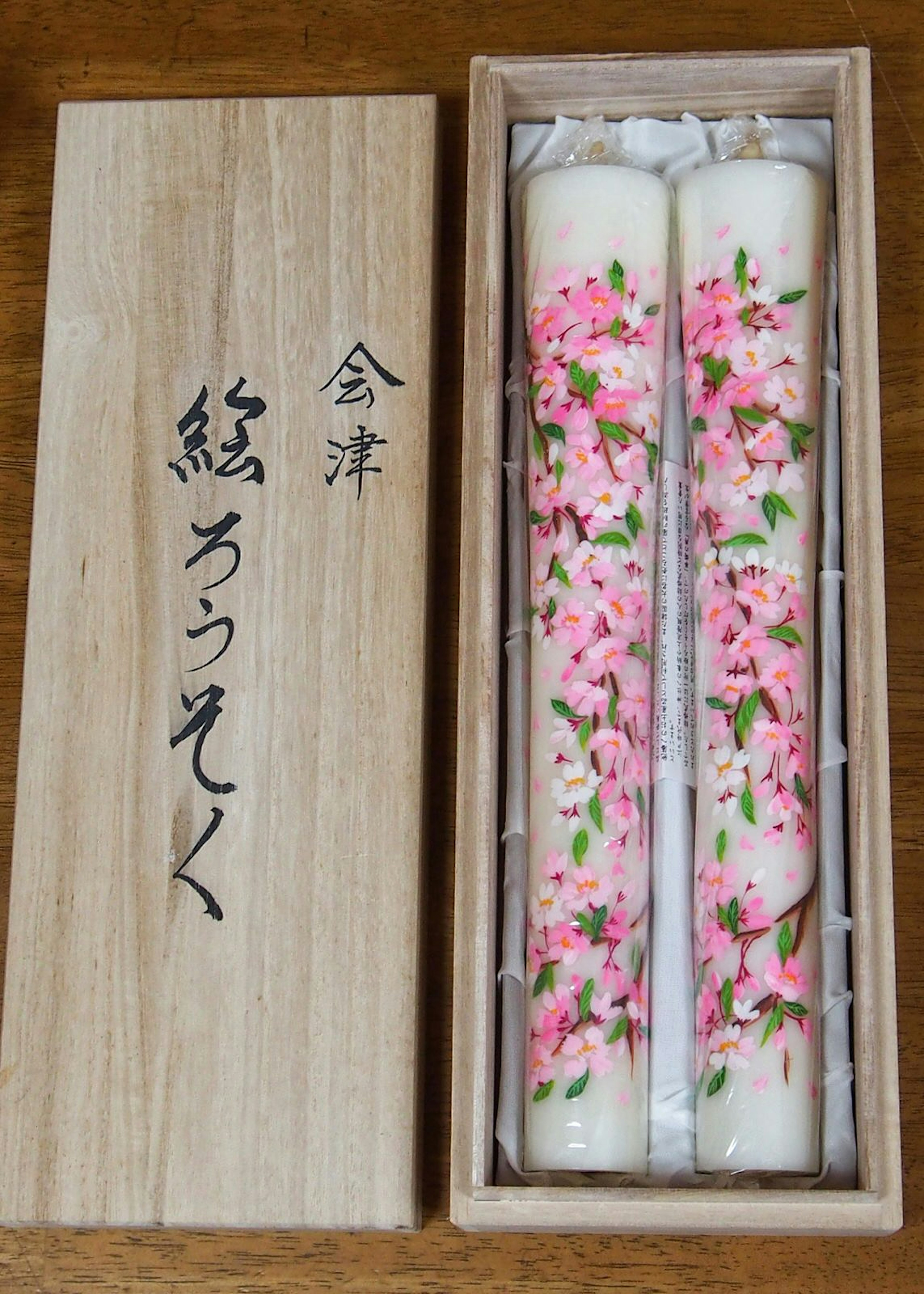 Two Aizu Erōsoku candles, finely painted with pink blossoms, presented in a wooden box at studio Yamada Shōten © Manami Okazaki / Lonely Planet