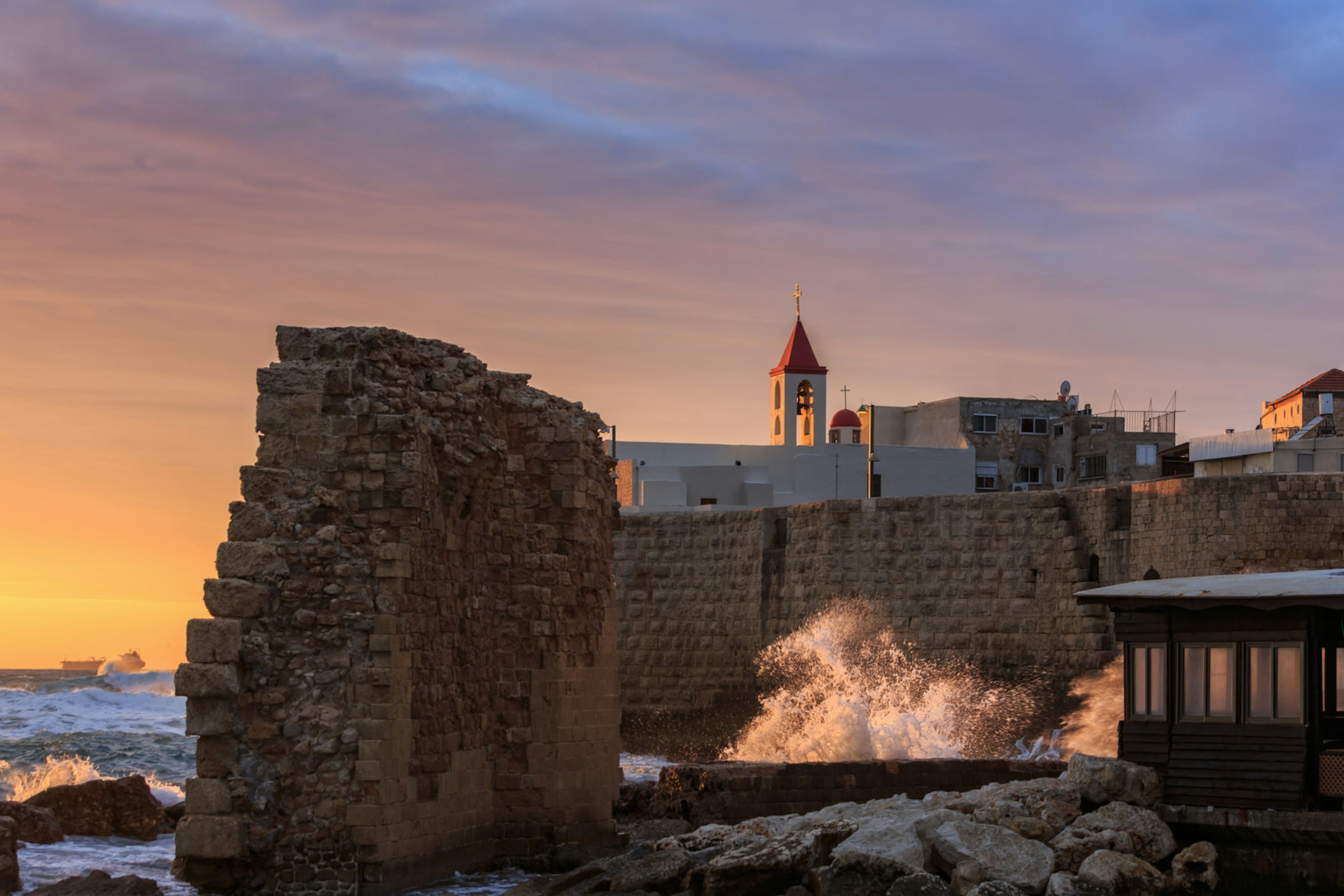 Evening view of the Greek orthodox church and remains of ancient harbour wall in Akko, Israel. Image by Roka / Shutterstock