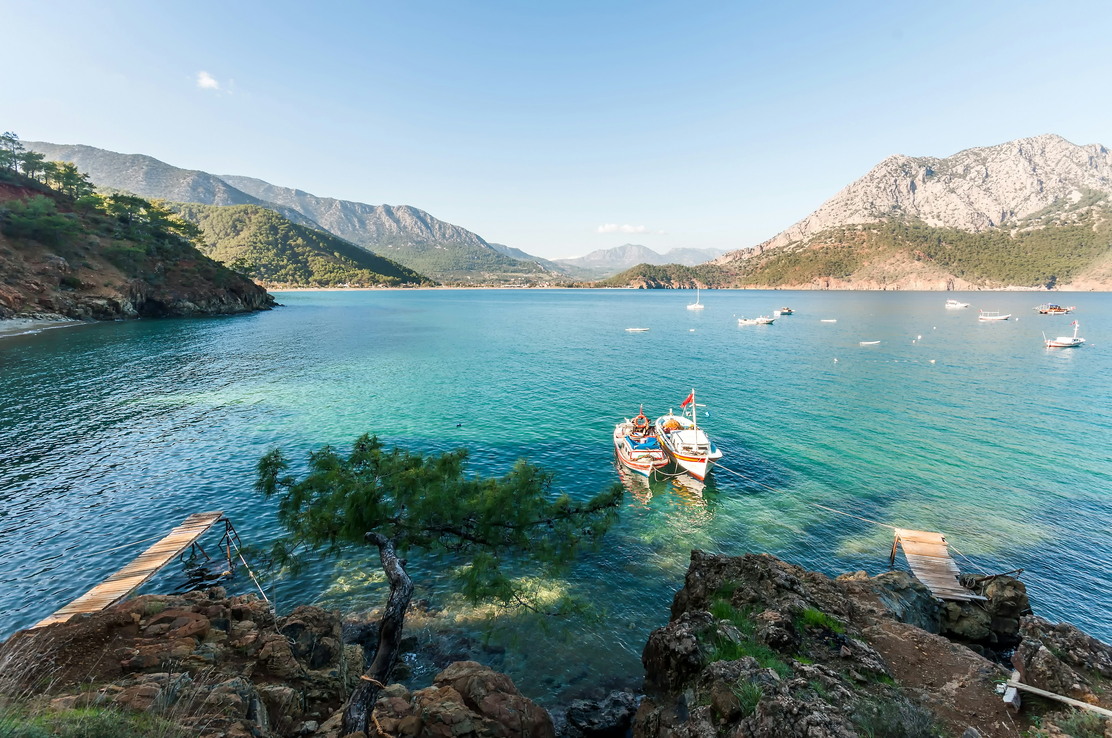 Boats float in turquoise water with a rocky shore surrounding.