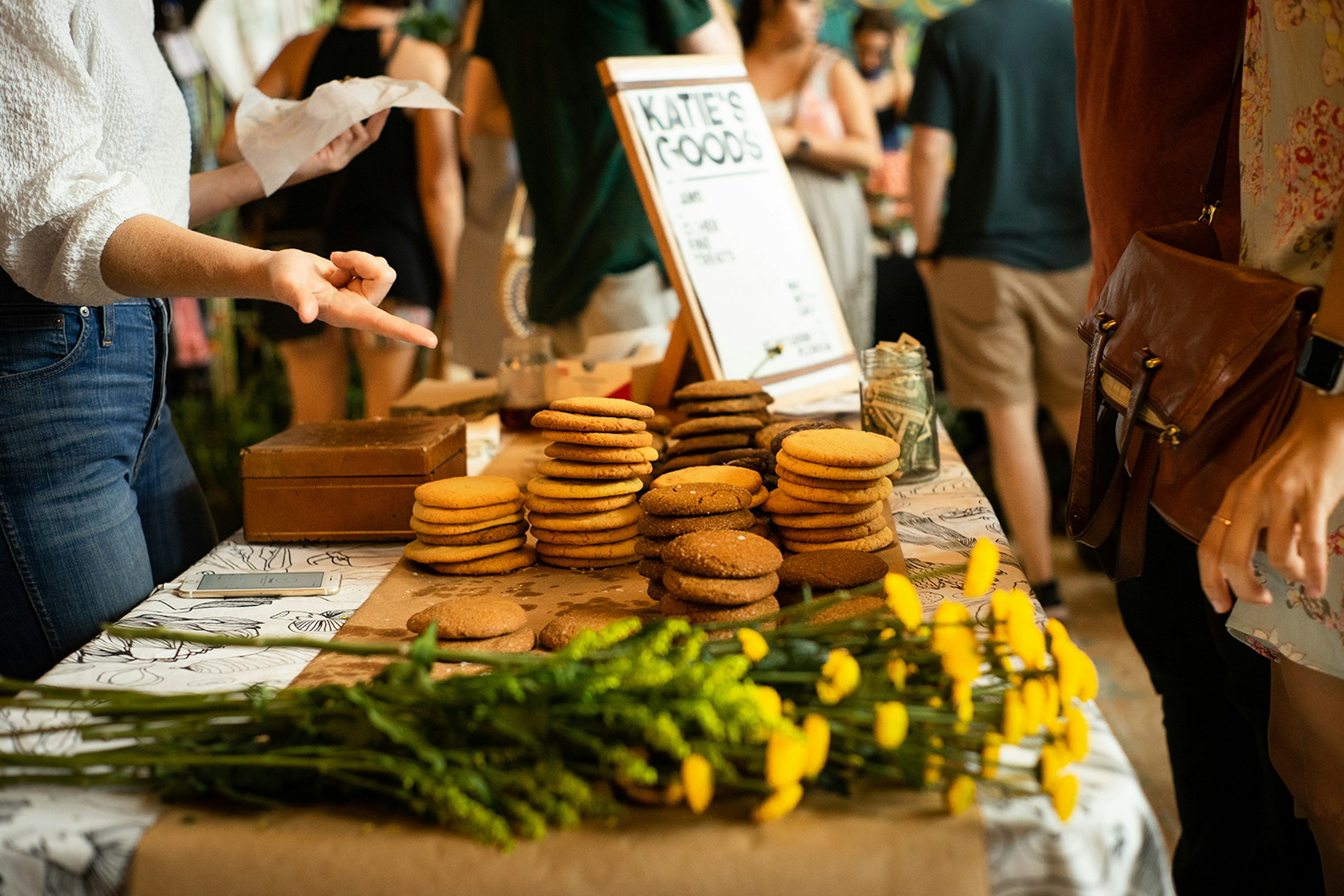 Table with a bunch of yellow flowers and a range of locally baked cookies at Indie Flea in Tampa © Dominic Cador / Lonely Planet