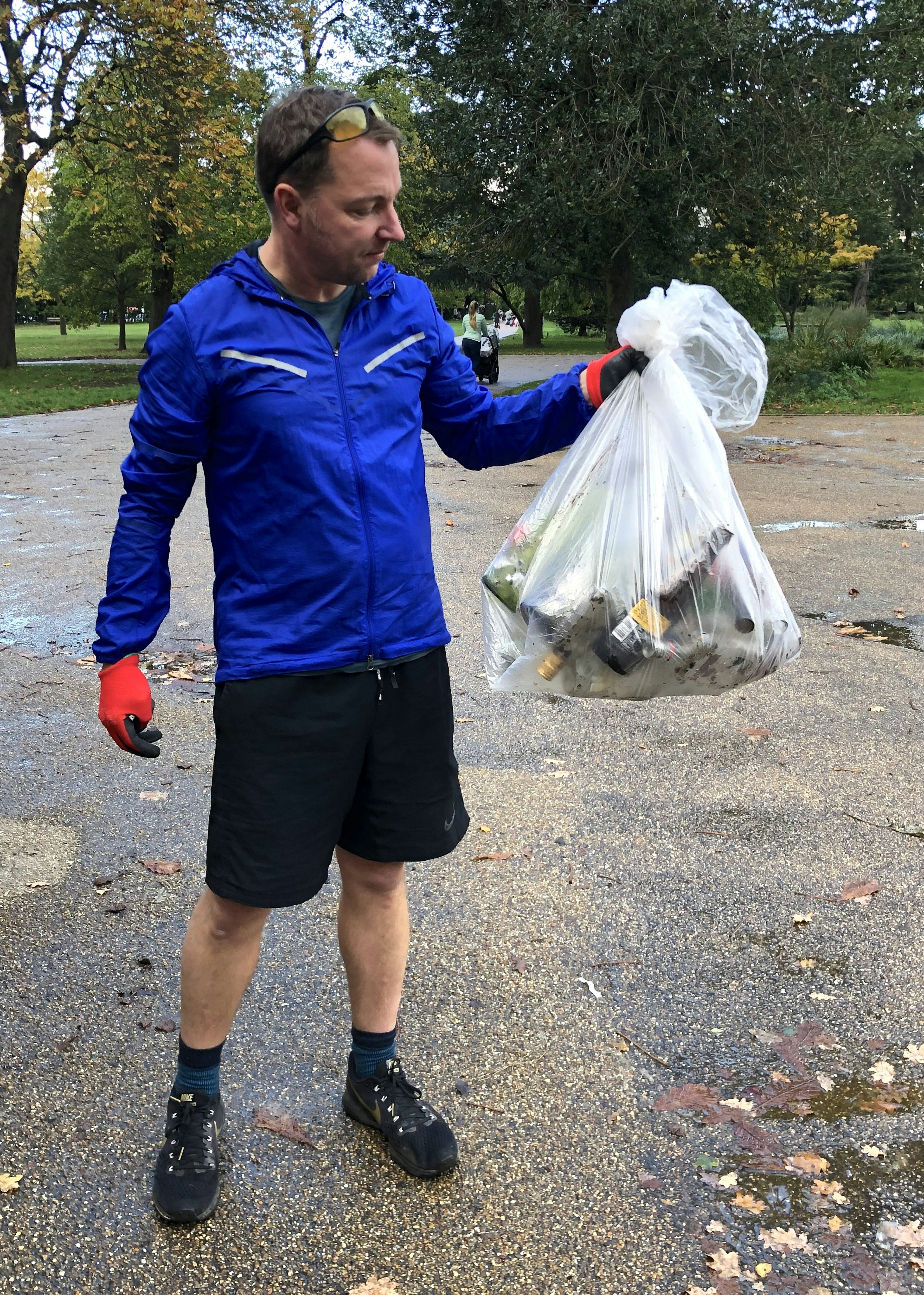 The author of the article stands in a park, staring at a large bag of rubbish he holds in his hand.