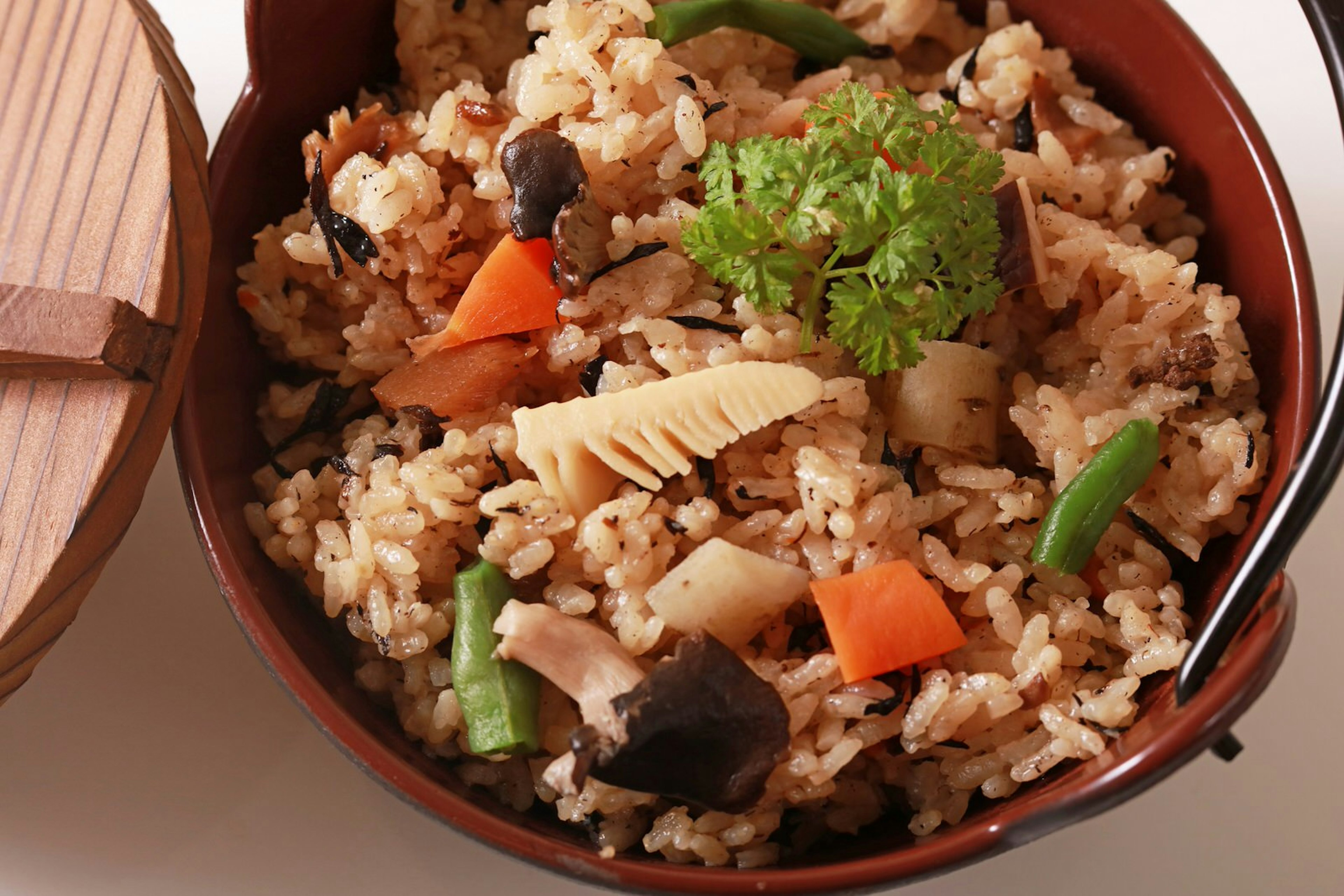 Close up of a bowl of takikomo gohan, a dish of mixed steamed rice with bamboo shoots and other vegetables