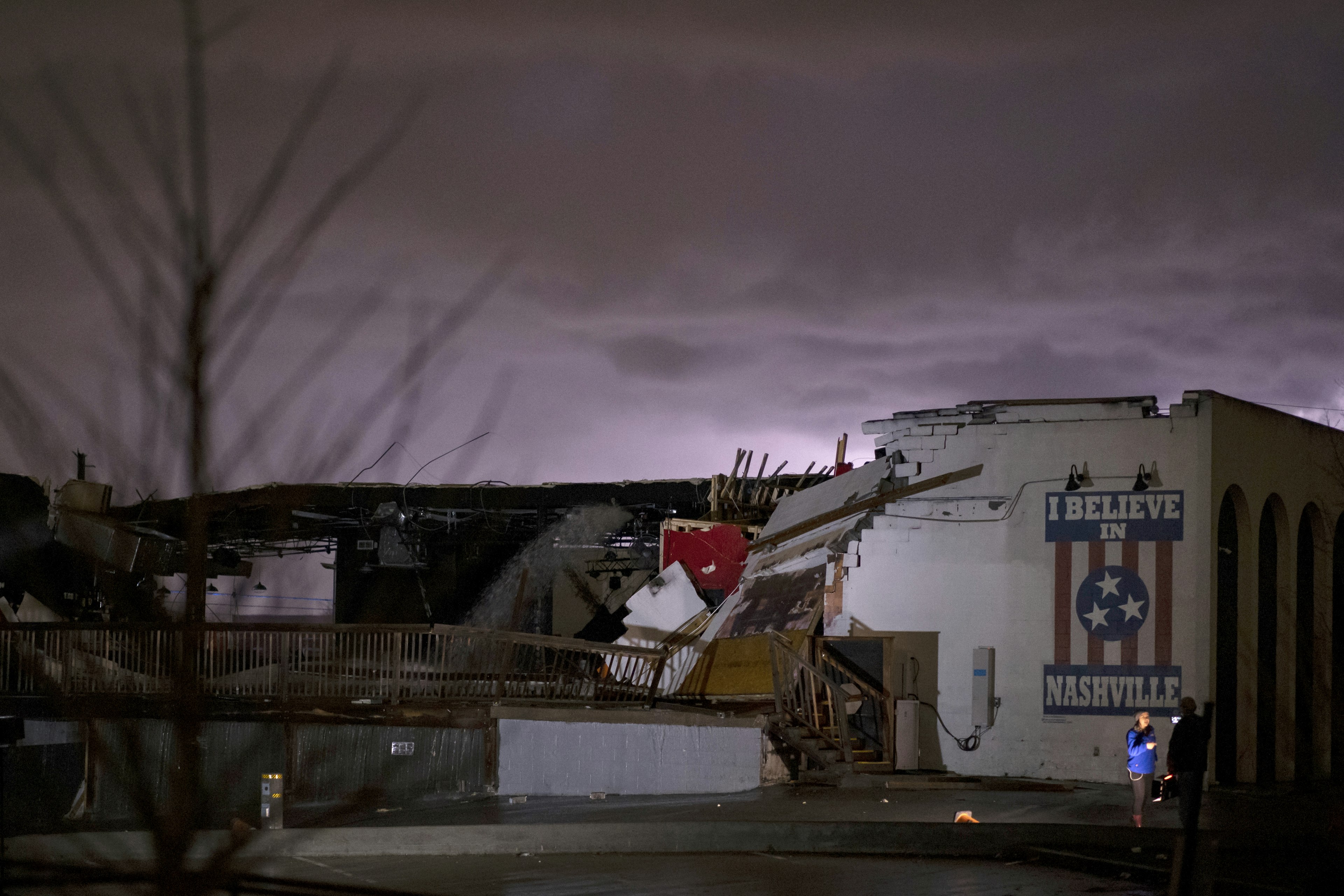 An eerie purple sky glows over a white brick wall with a mural reading I Believe in Nashville, one of the only parts of the Basement East facade still standing after the Nashville tornados