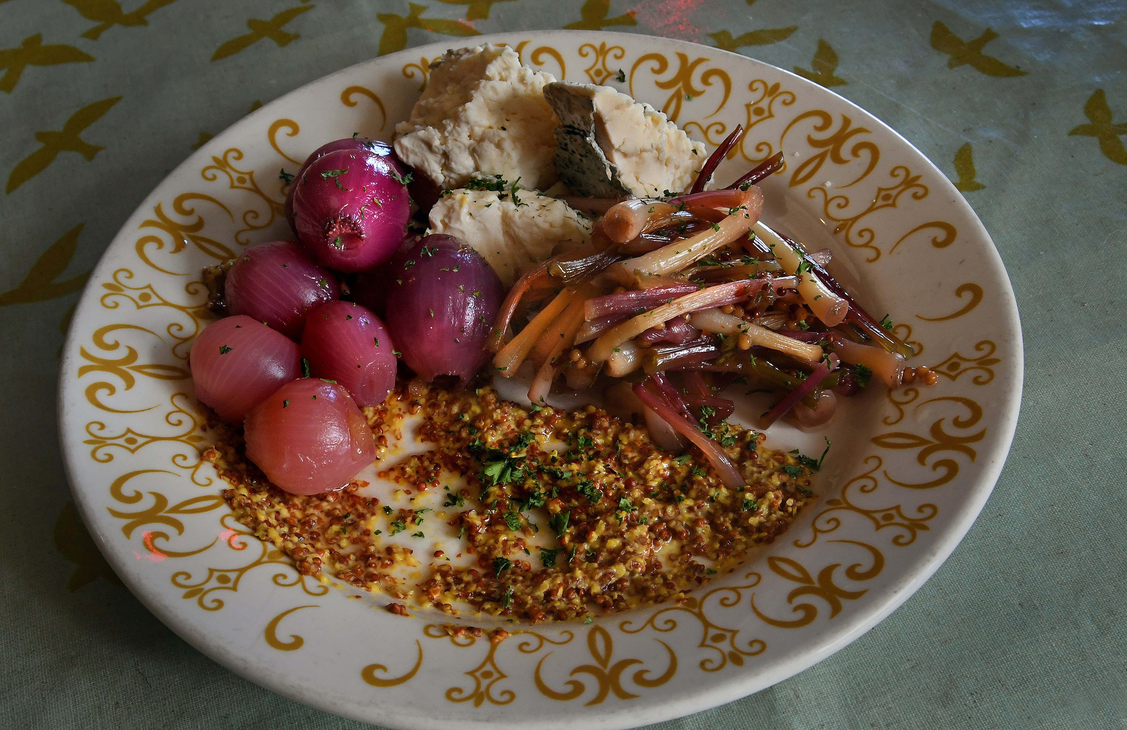 A white plate rimmed with an ornate gold design is filled with colorful vegetables in a farm to-table dish at Bluegrass Kitchen in Charleston, West Virginia