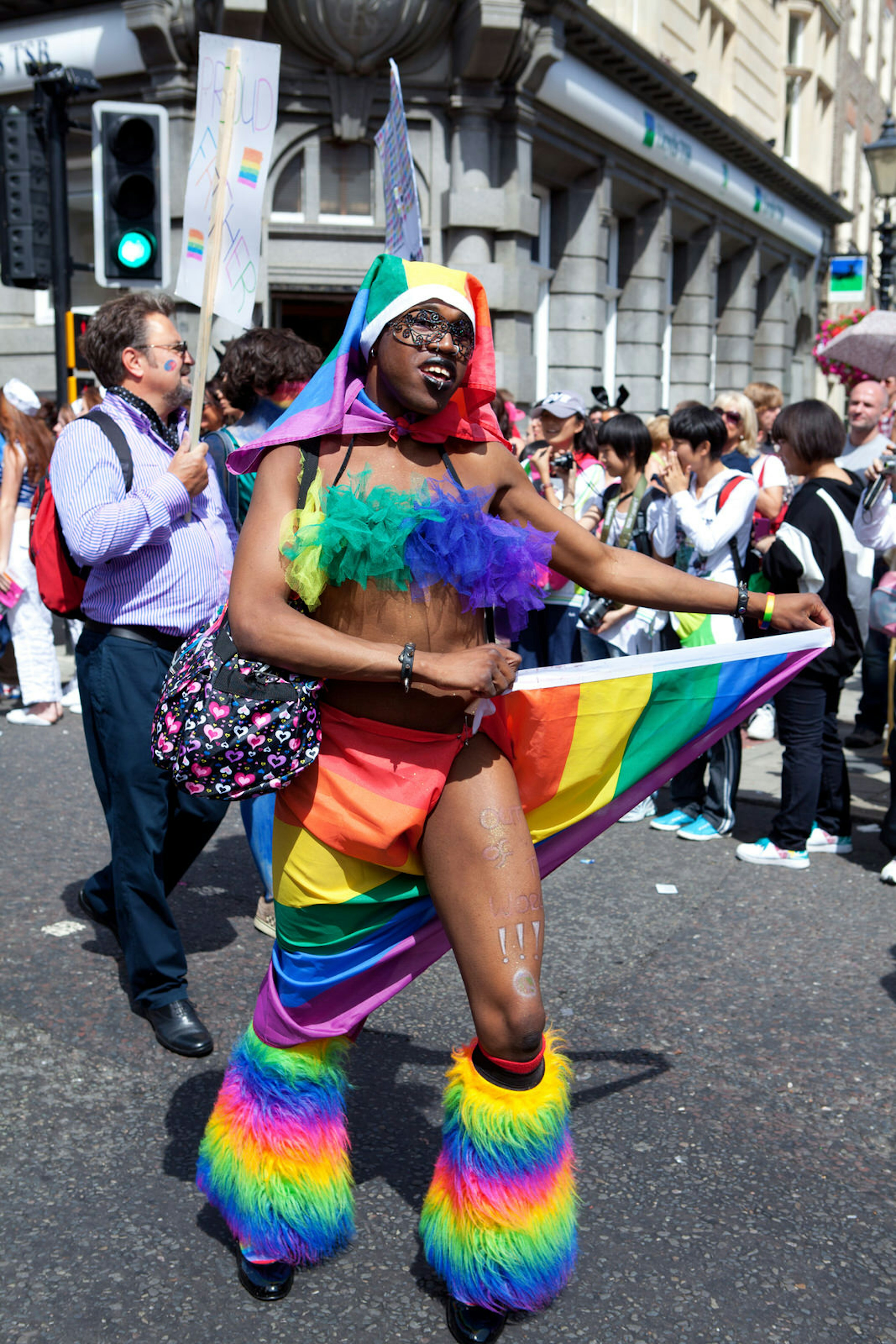 A dancer at the Brighton Pride parade dressed head to toe in rainbows, while crowds watch