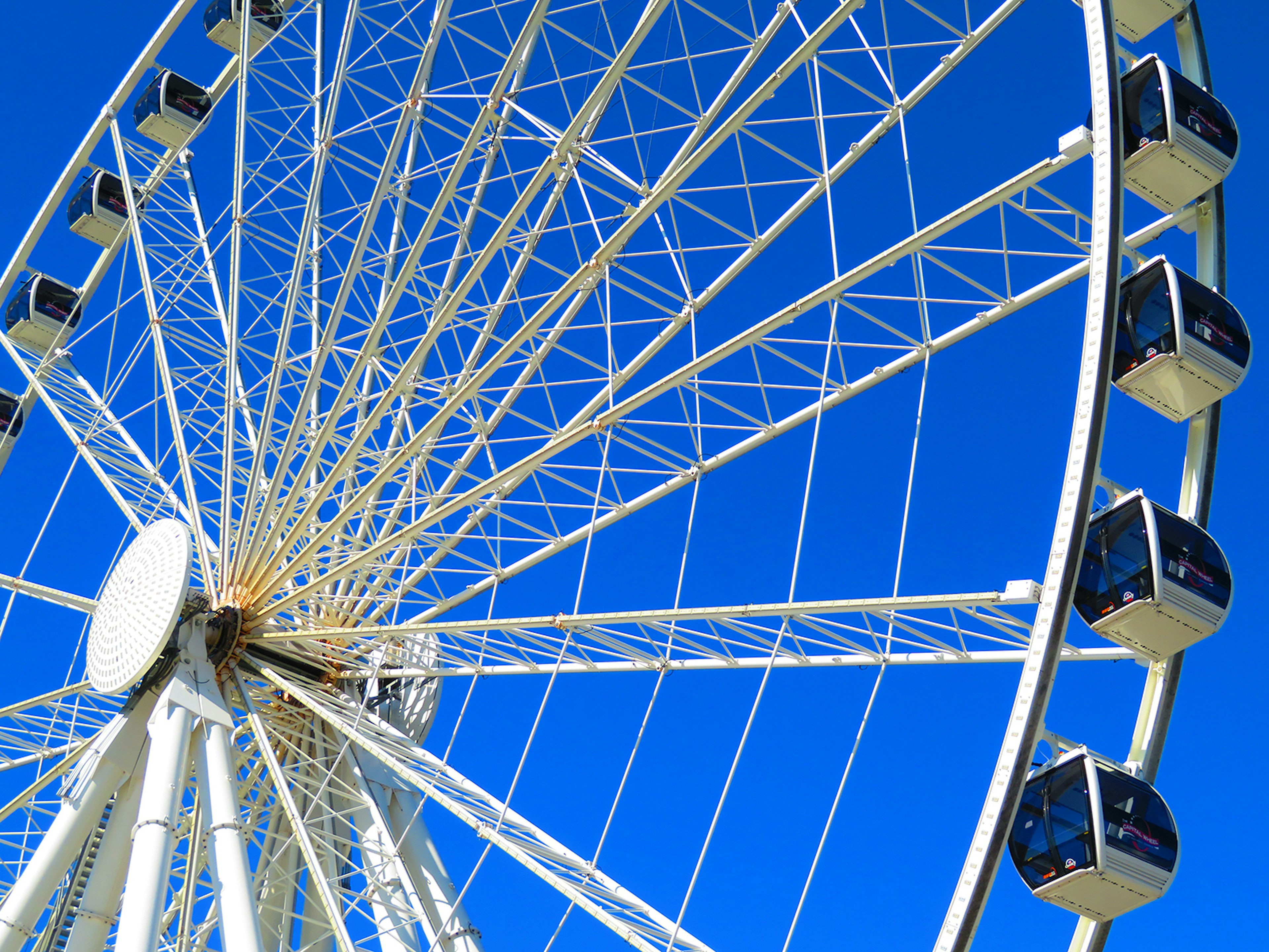 Close-up of white Ferris wheel, the Capital Wheel in National Harbor, against a bright blue sky