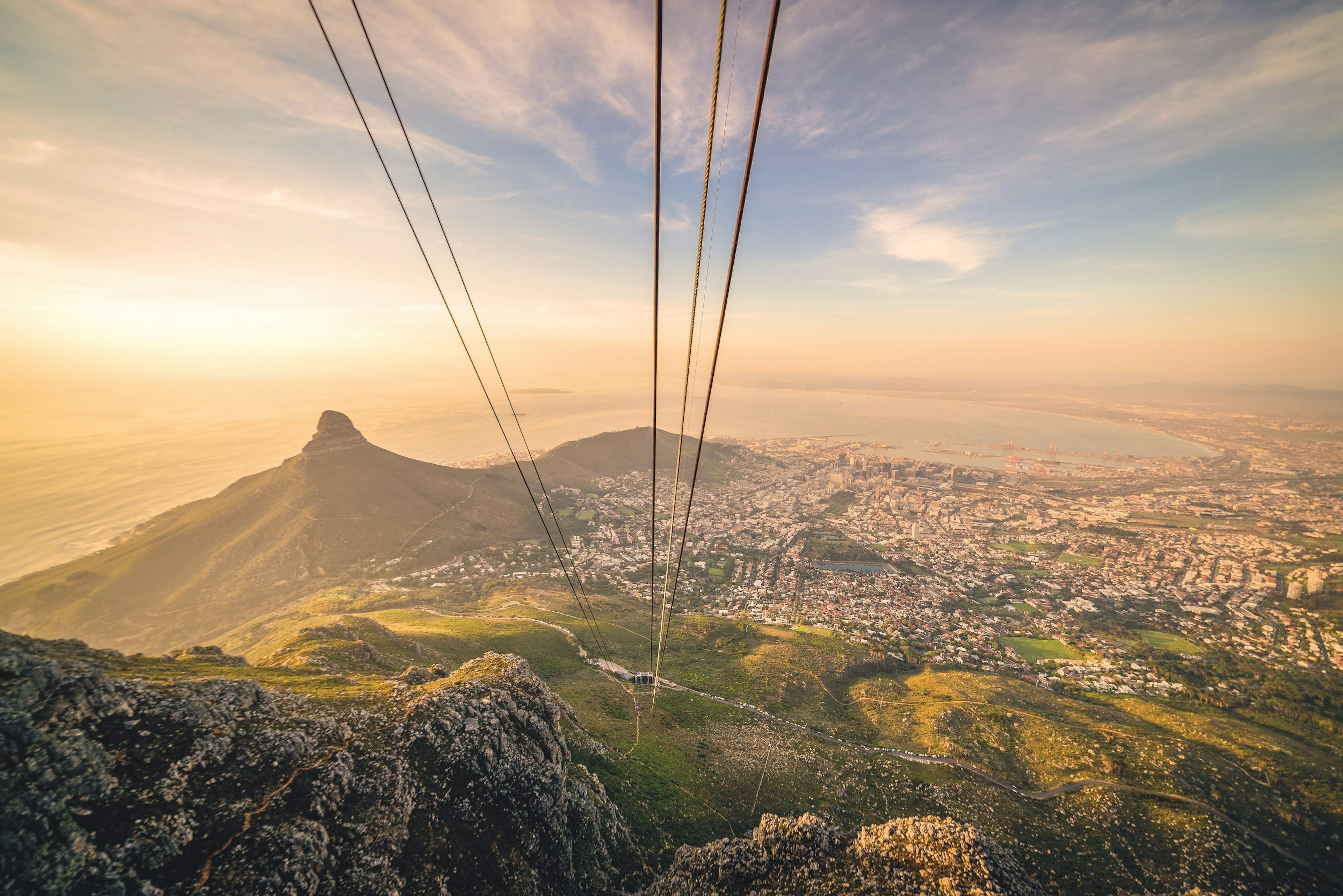 View of Cape Town taken from within the cable car on approach to the top of Table Mountain. The cables of the carbon-neutral cableway are overhead.