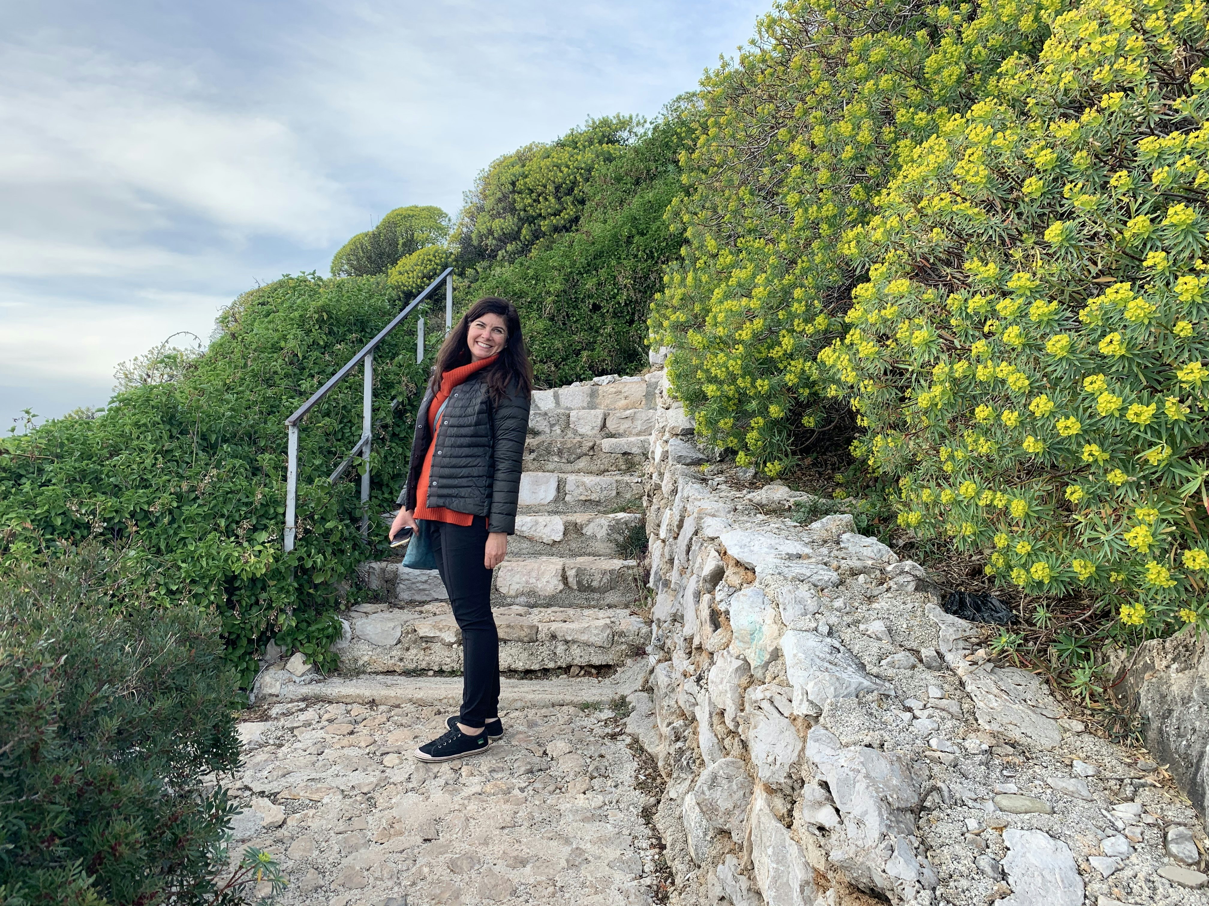 A woman stands on stairs next to flowers