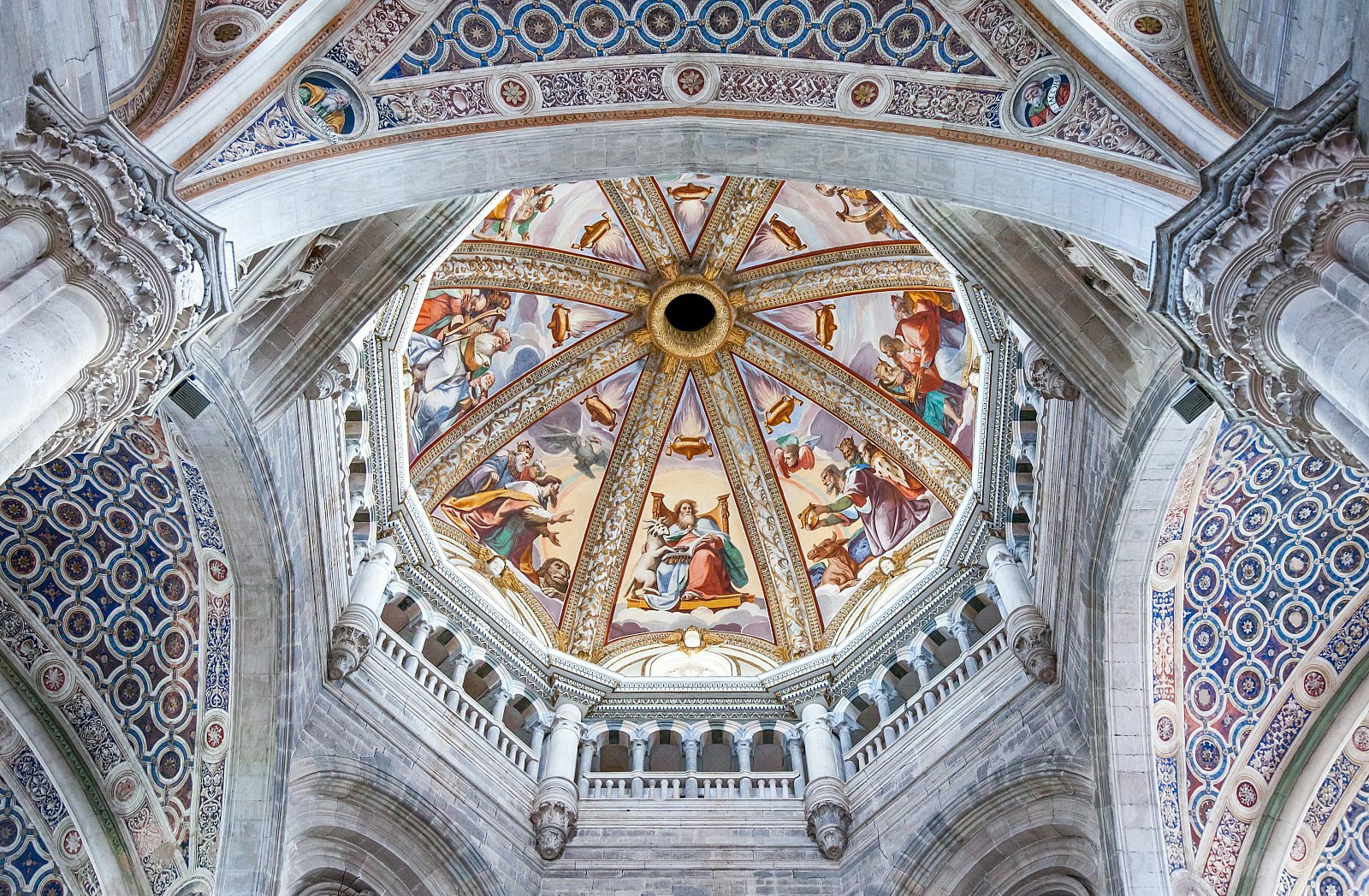 The ceiling of the main nave of the Certosa di Pavia; it is domed and vaulted, and covered in detailed and colourful frescoes and tilework.