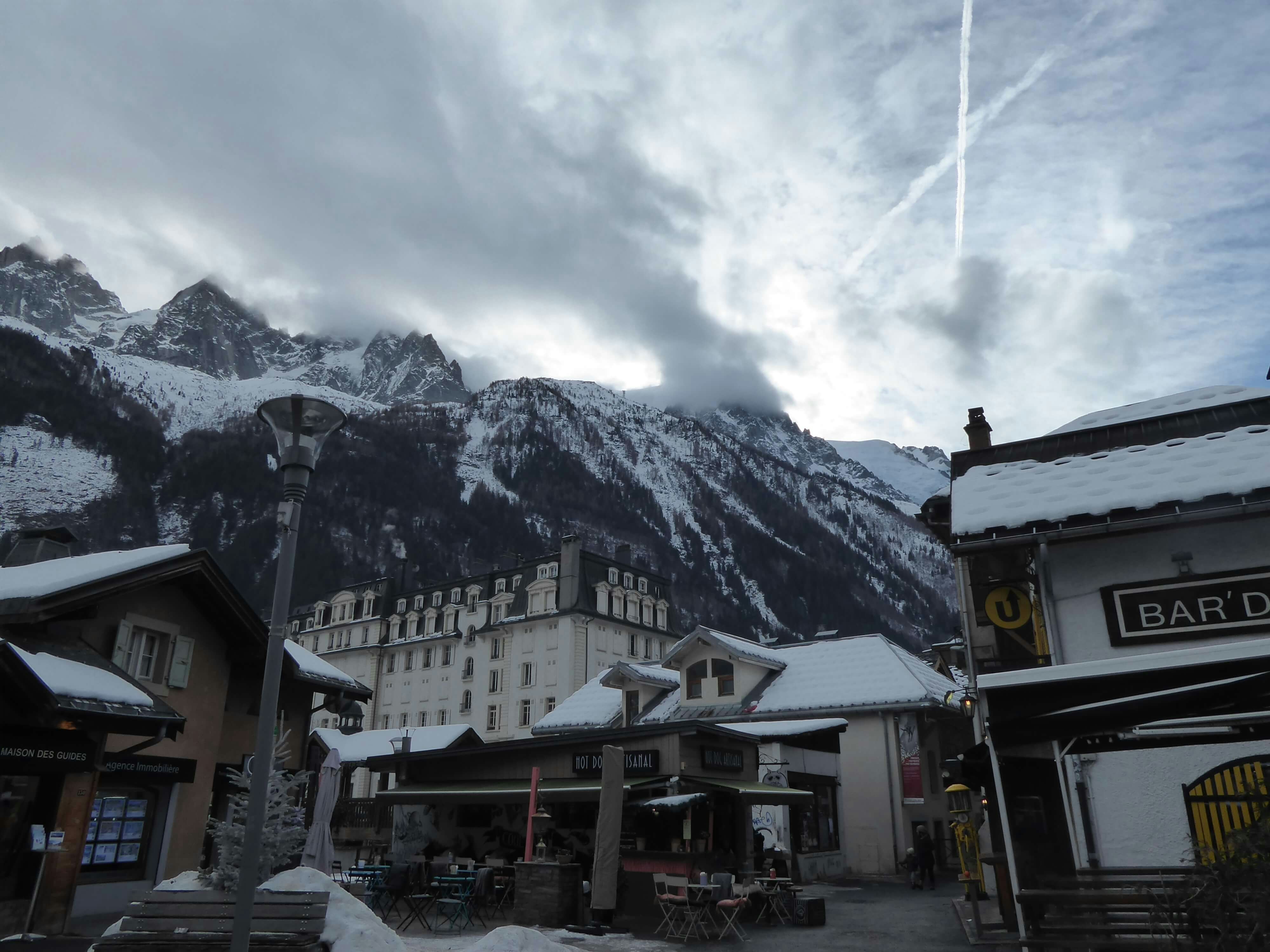 A village on dark day. There are clouds overhead and the mountains in the background.