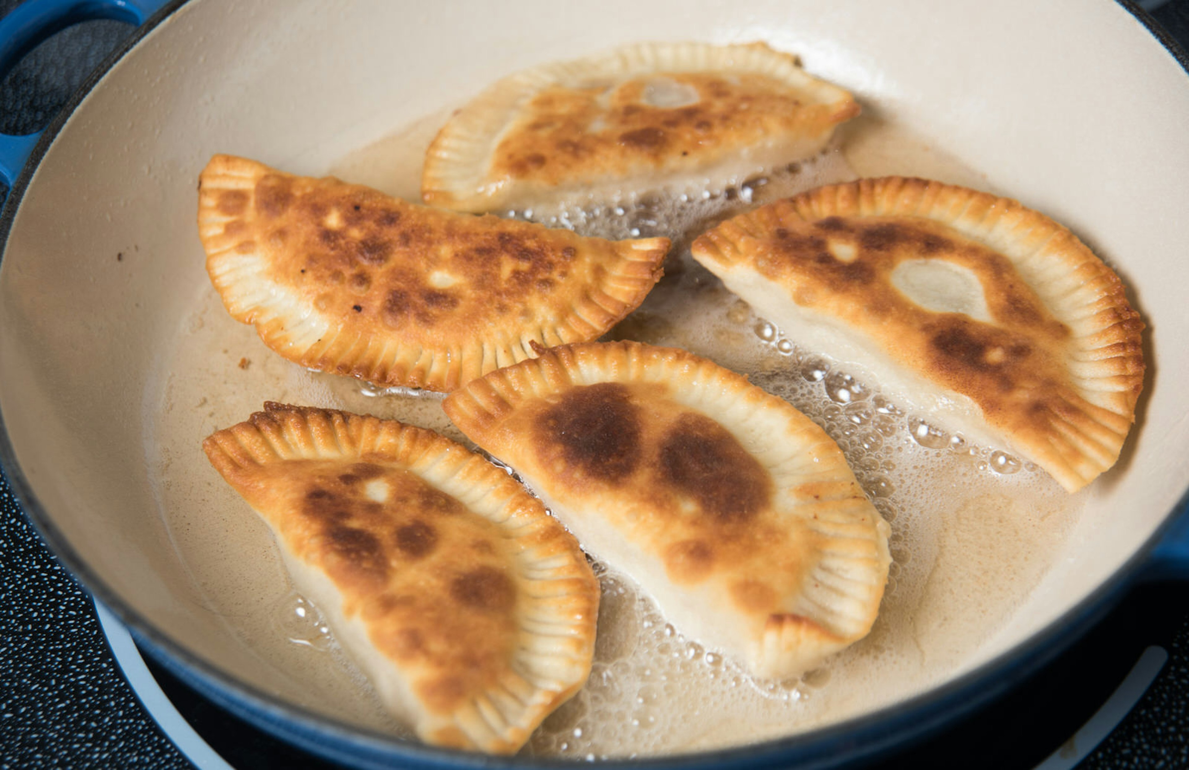 Crescent-shaped pastries sizzling in oil