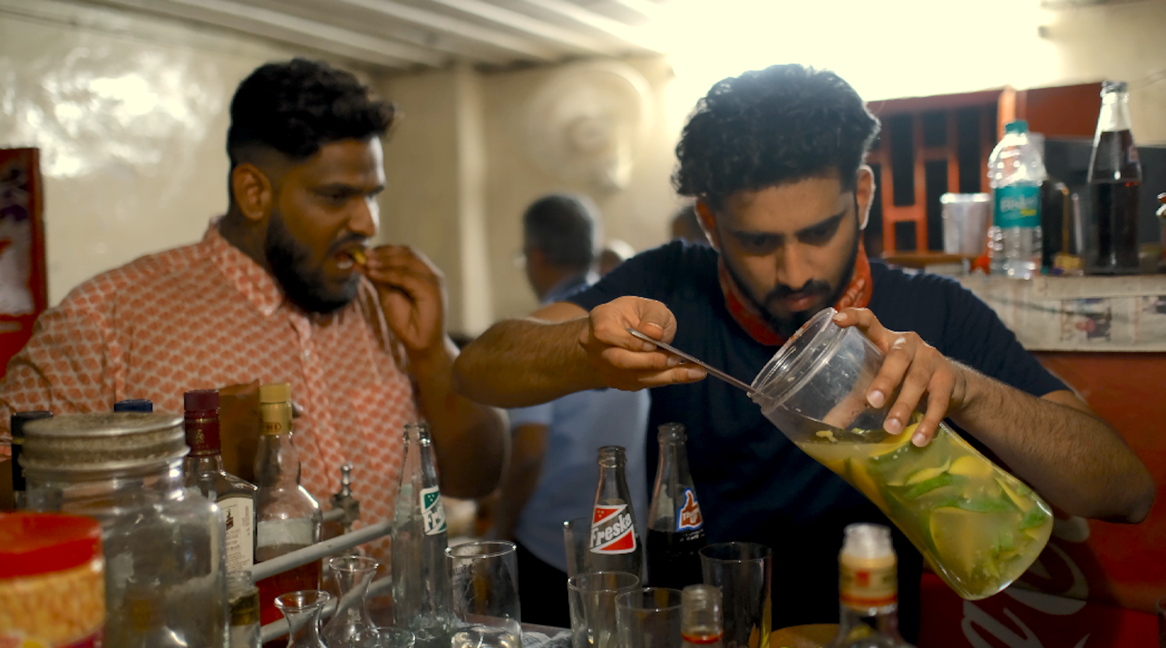 A man fishes briny mango slices called chepplin torran out of a jar at a tavern in Goa, India