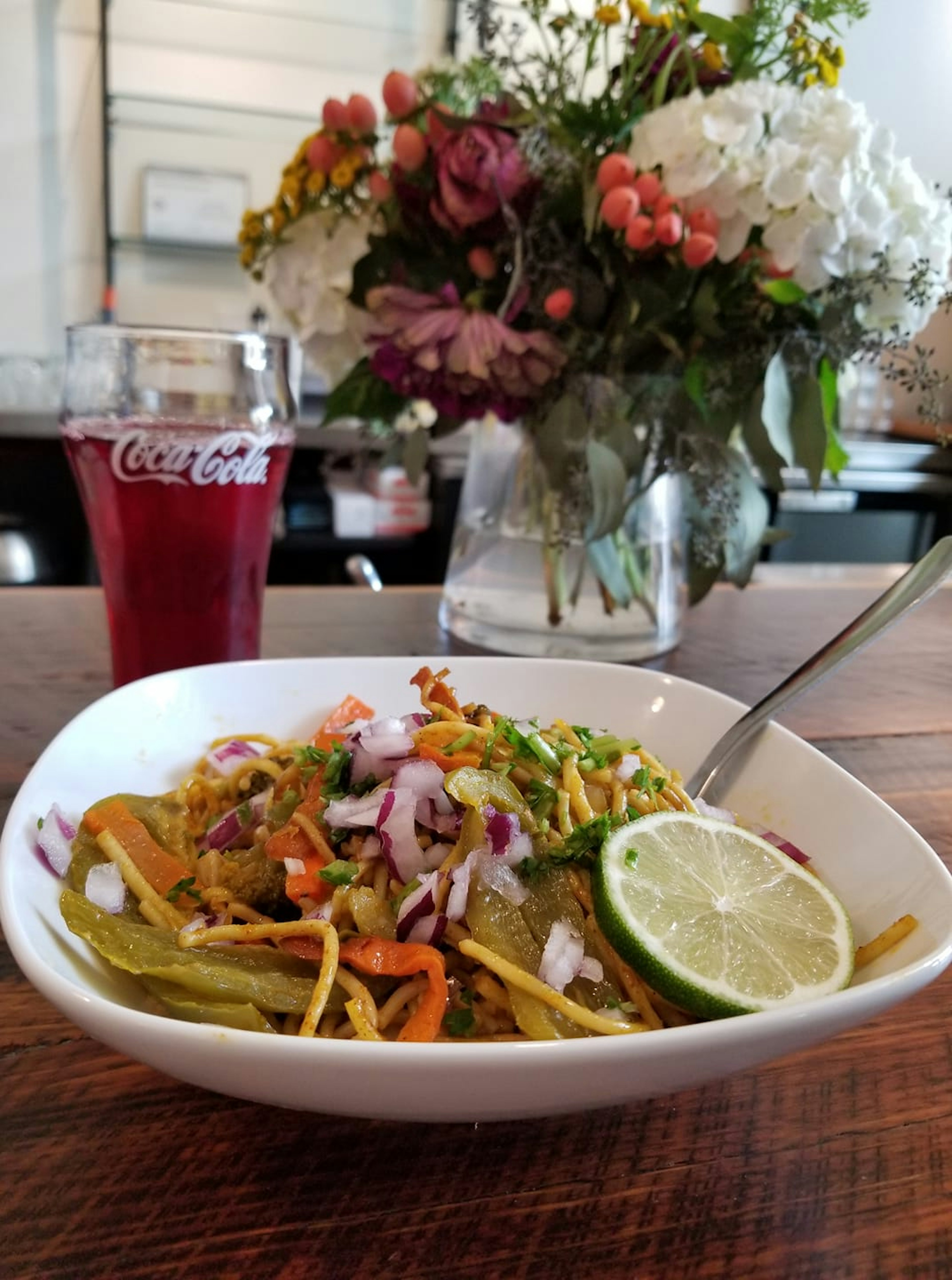 A plate of chow mein and a coke are displayed on a table © Andrea Fenise