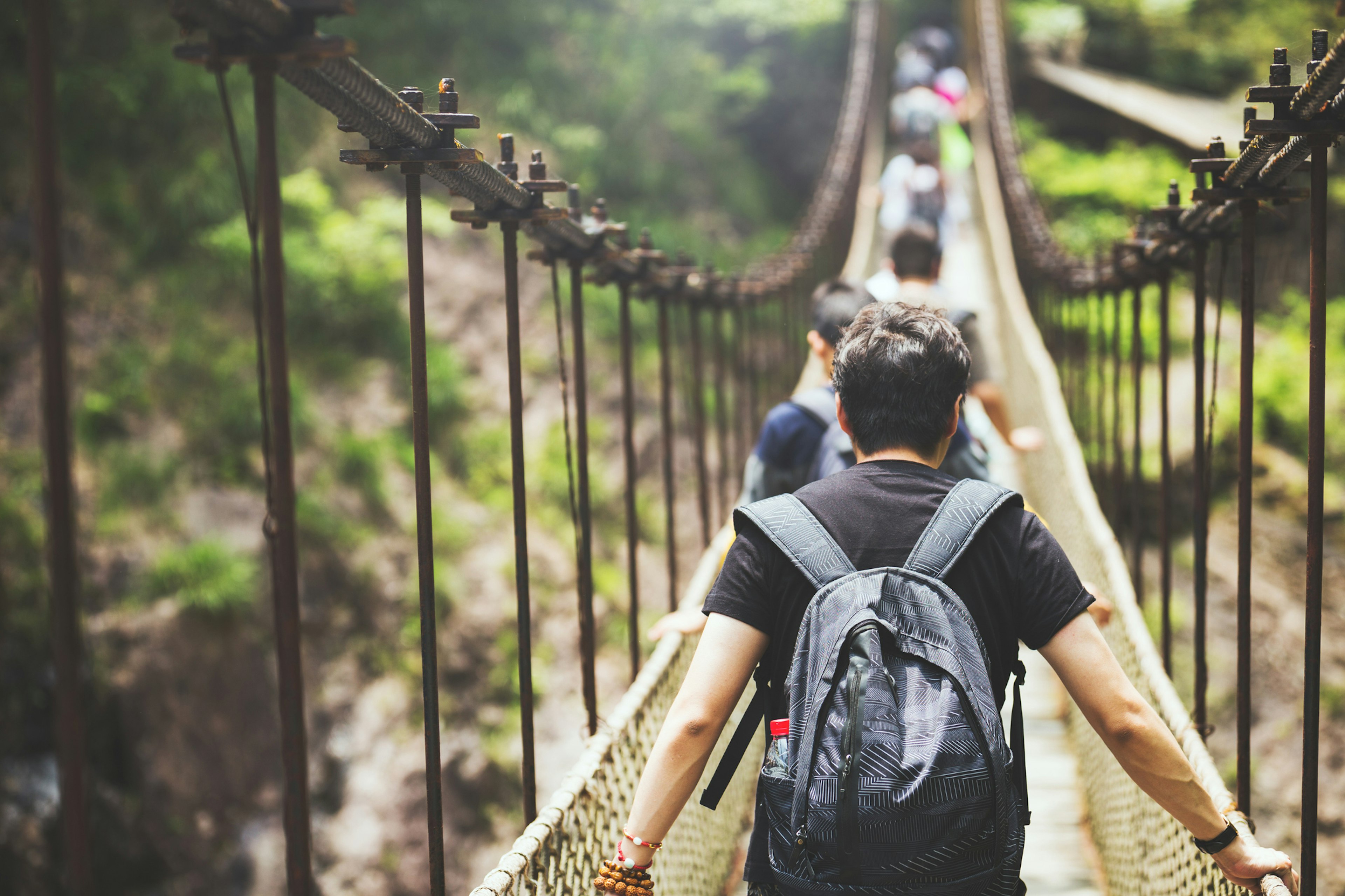 A close-up photo shows people walking along a suspension bridge.