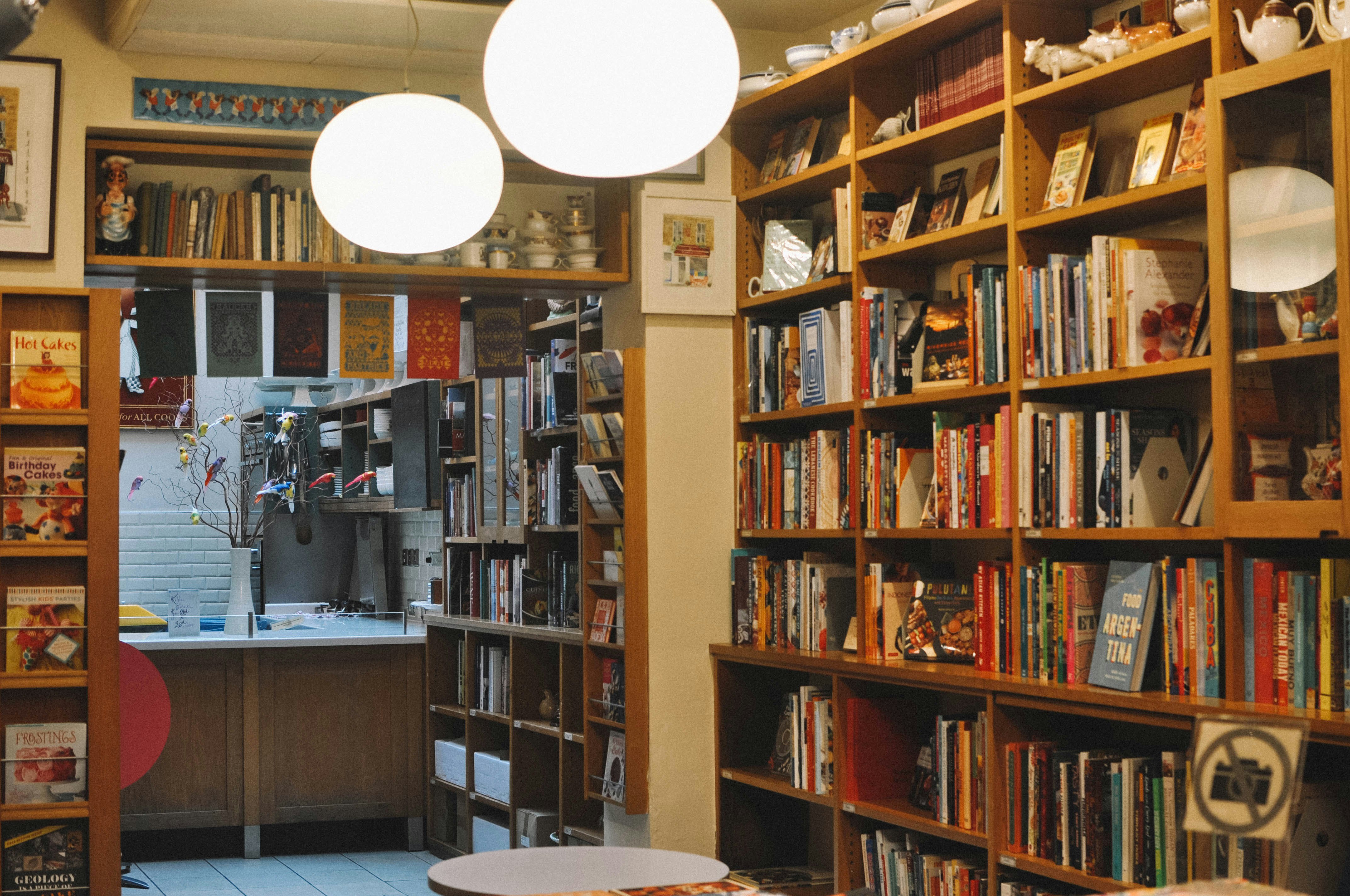 Walls filled with cookbooks, leading out to a different room with a clean, white-tiled kitchen.