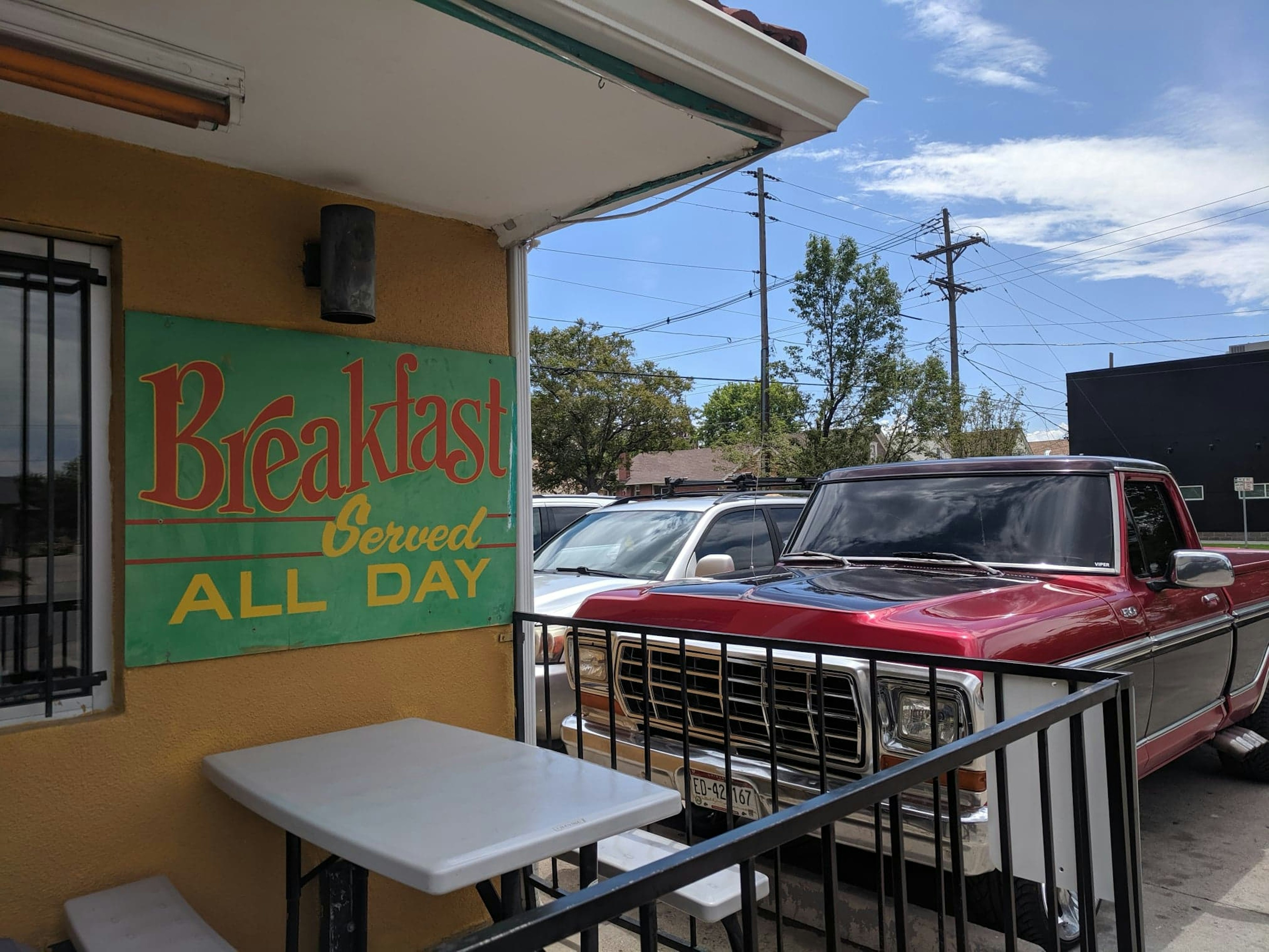 The bright yellow exterior of El Taco De Mexico appears behind a teal sign reading