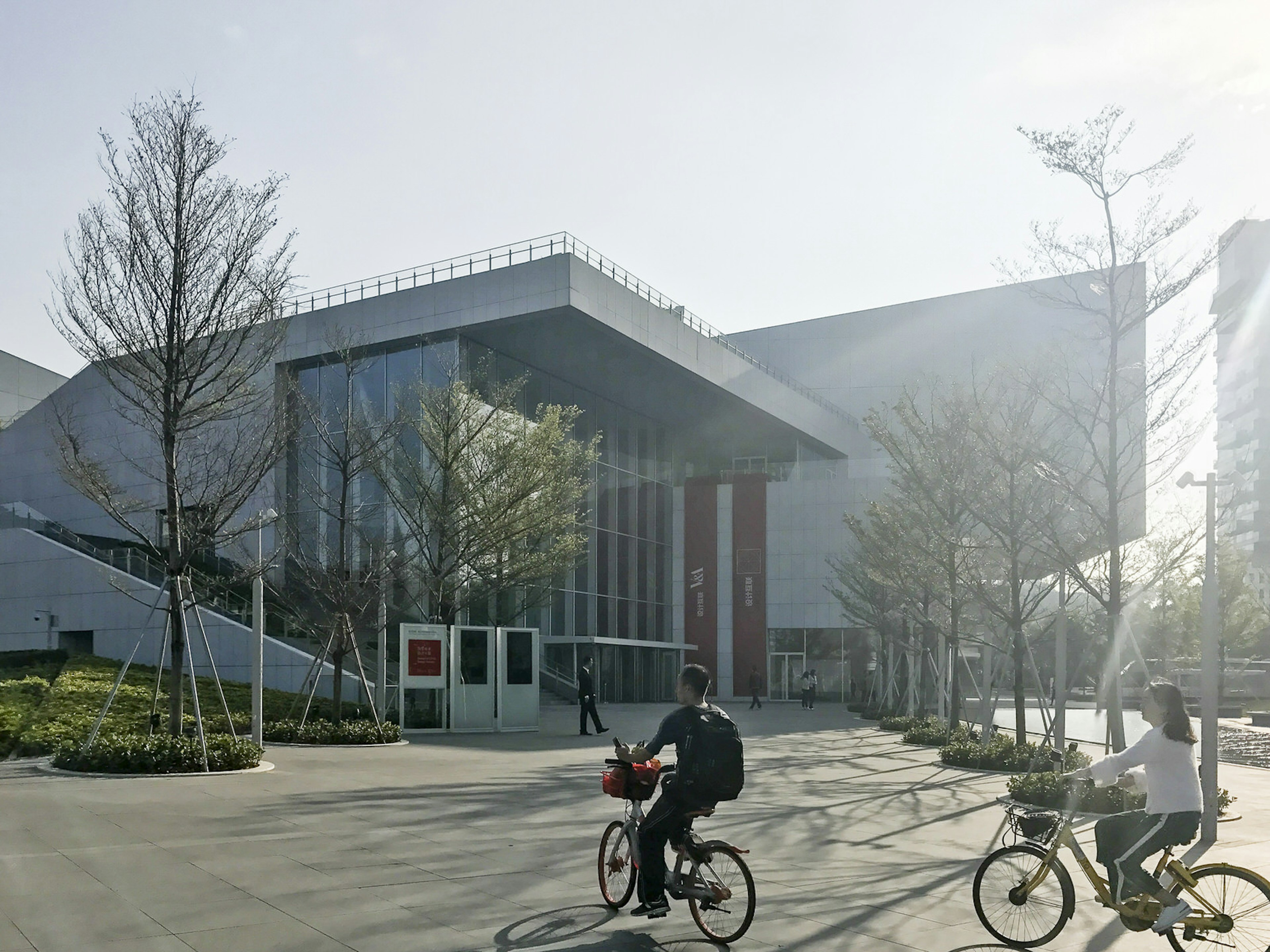 Two cyclists on city bikes ride in front of a glass and metal building. Design Society: an arts centre opened in 2017 in collaboration with the V&A © Cathy Adams / iBestTravel