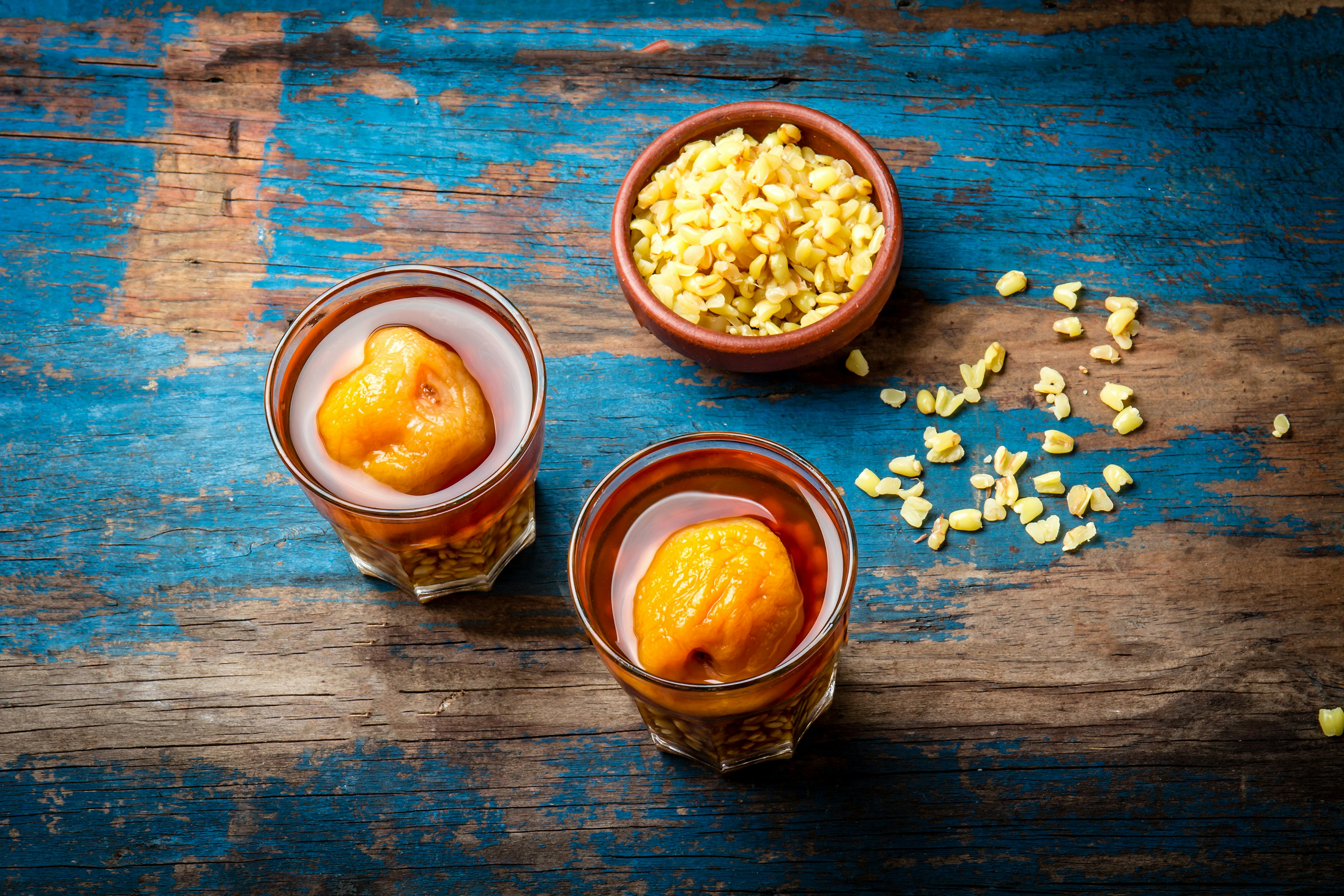 843488264
chilean drink, huesillo, chilean independence
Mote con huesillo. Traditional Chilean drink made from cooked husked wheat and dried peach on wooden board, rustic blue background.