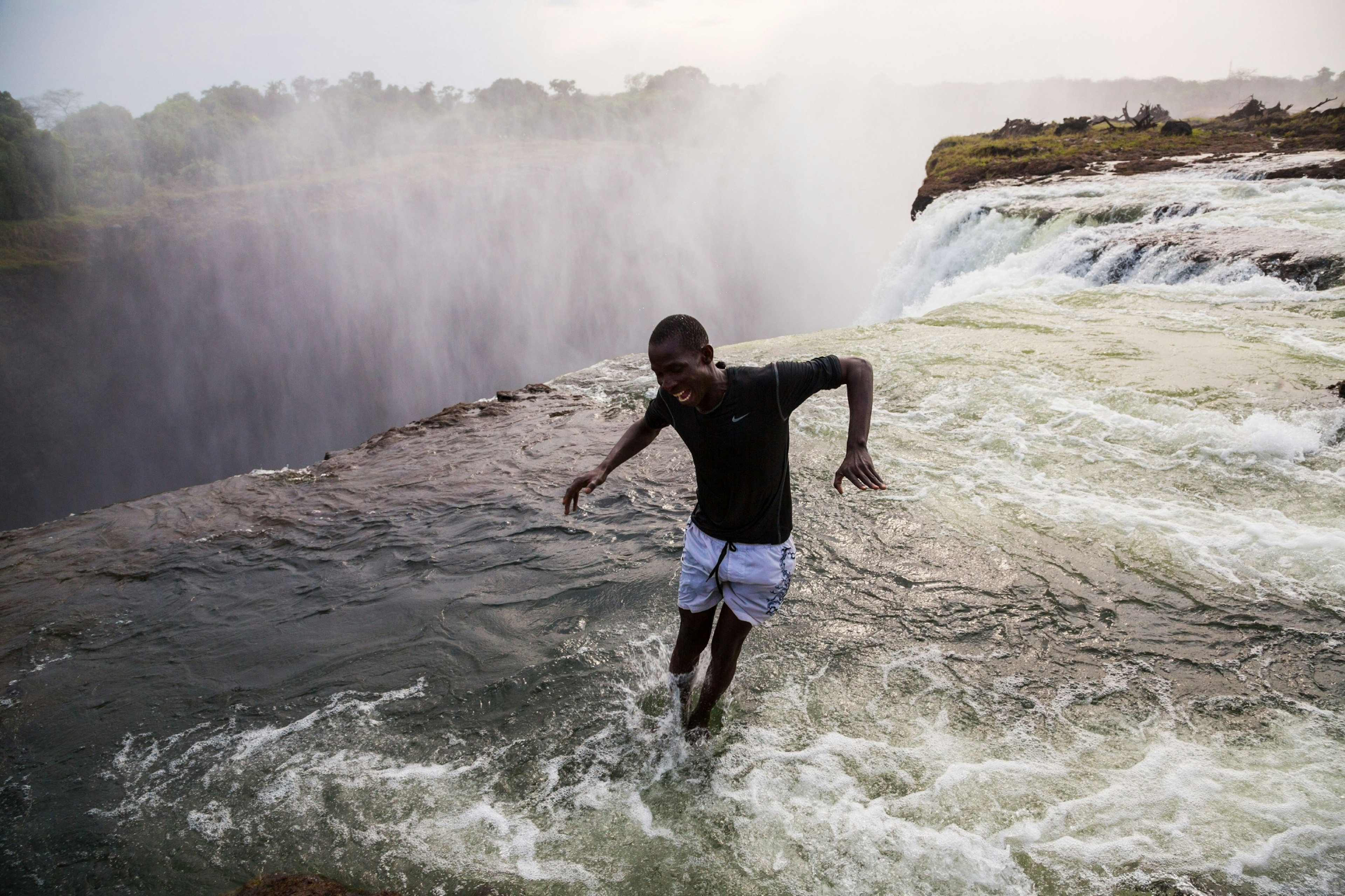 A man jumps into Devil's Pool in the Zambezi River at the top of Victoria Falls