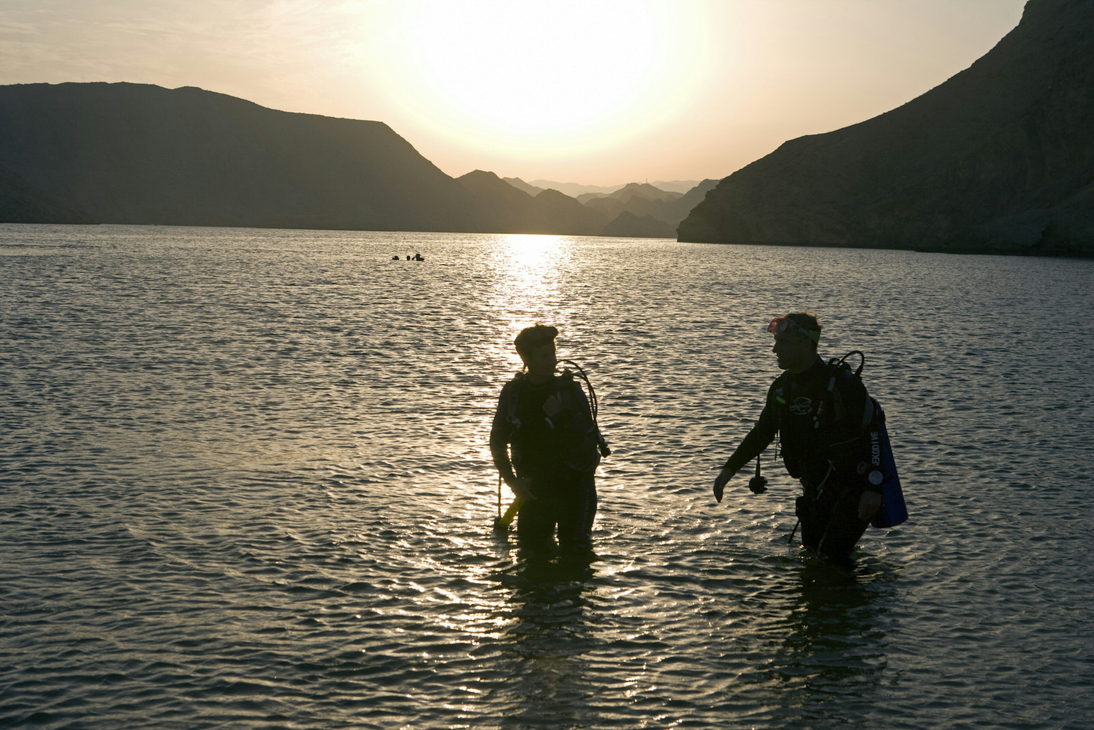 As the sun sets two divers exit the water after and evening dive on one of Omans many tropical reefs © Mark Hannaford / Getty Images