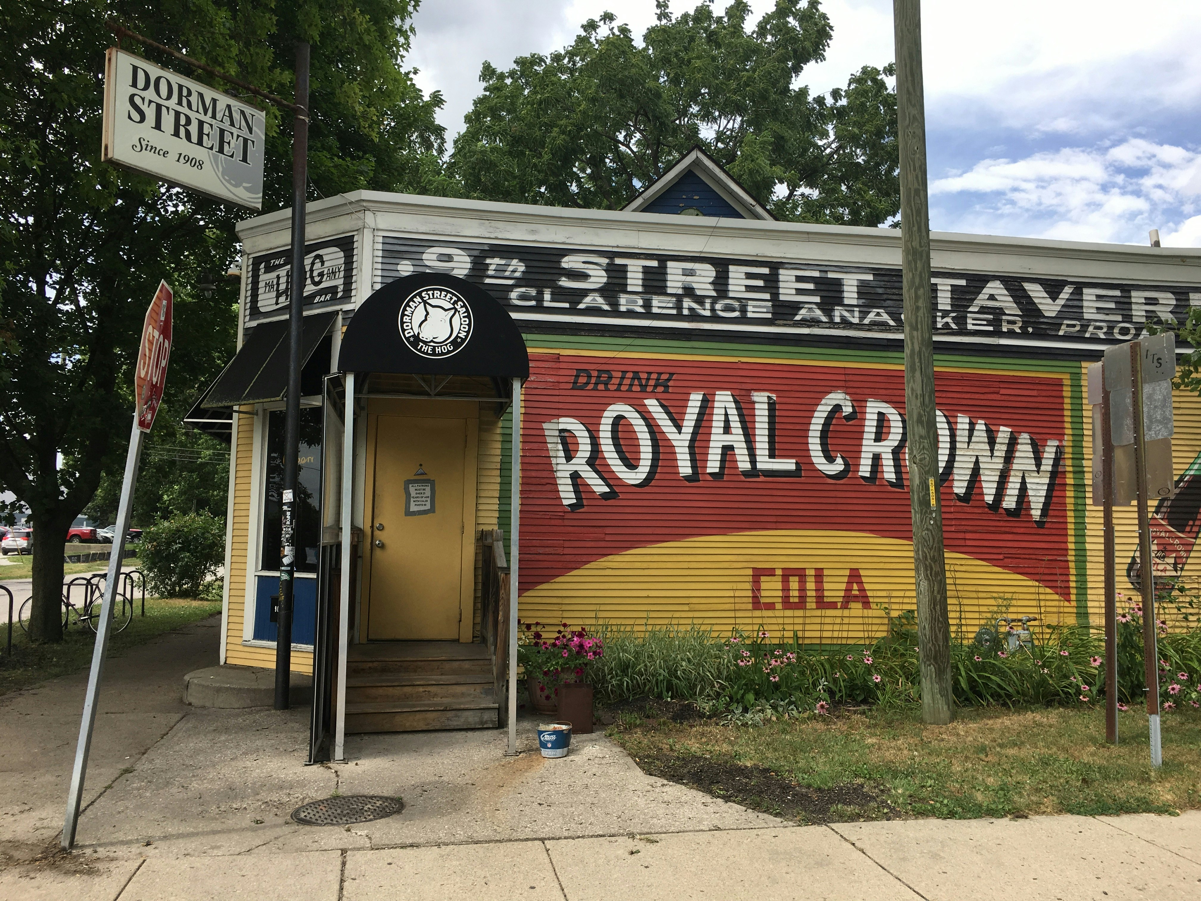 Exterior shot of the red and yellow wooden paneled Dorman Street tavern. There is a black awning above the entrance.