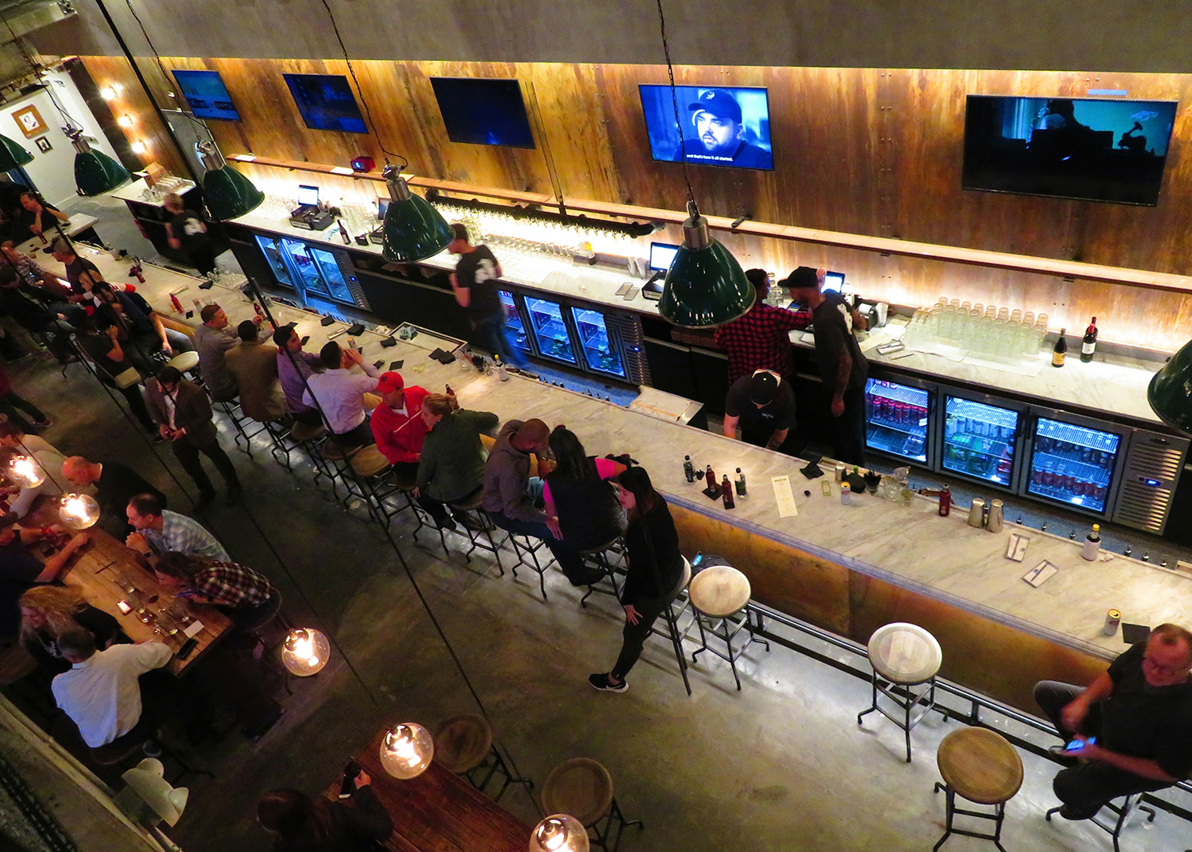 Aerial shot of people sitting on barstools in a dimly lit, modern wood-paneled bar © Barbara Noe Kennedy / iBestTravel