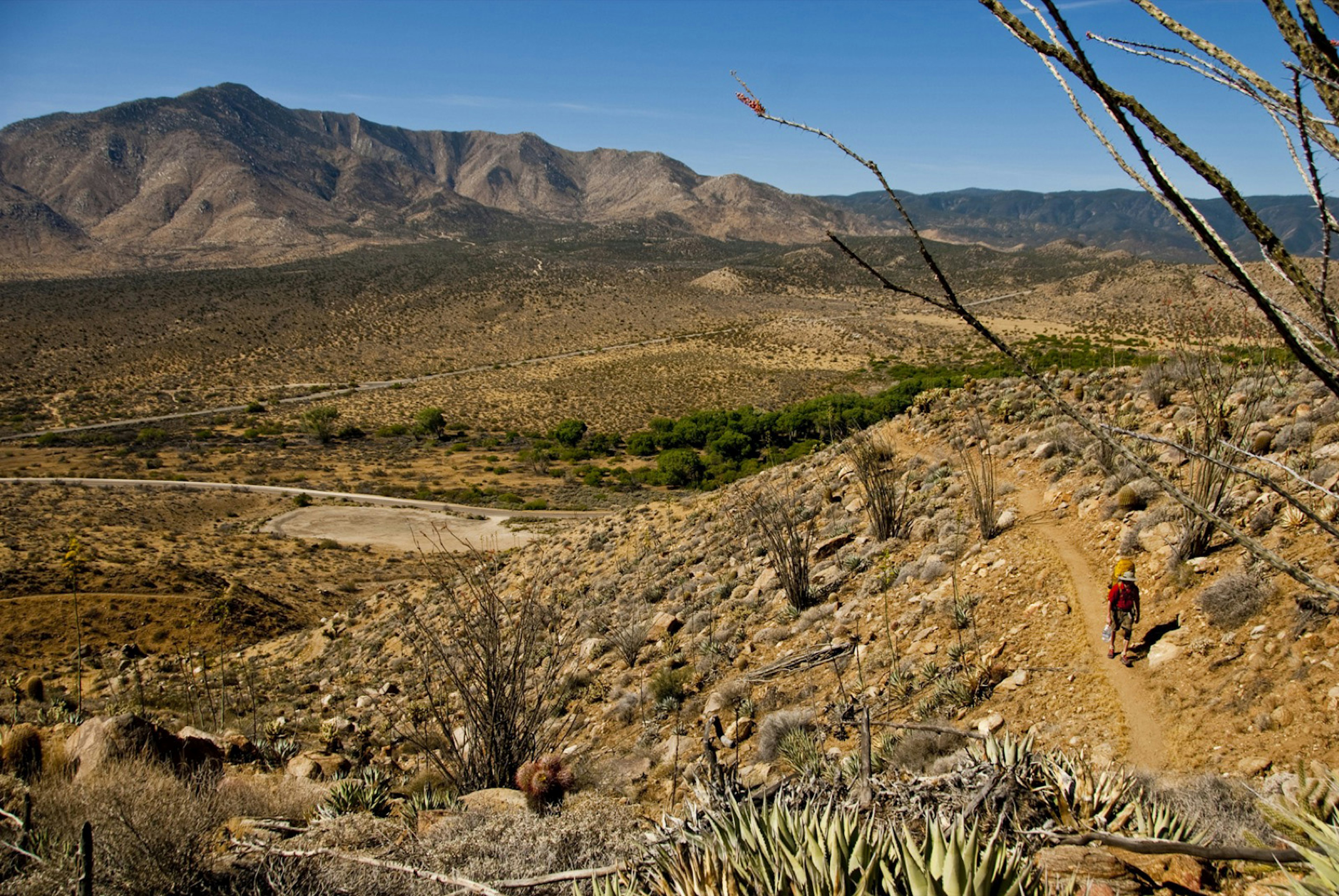 A dry scene in the deserts of Southern California, with large expanses of dust, stone and sage between low rocky hills on the Pacific Crest Trail © Sean Jansen / Lonely Planet